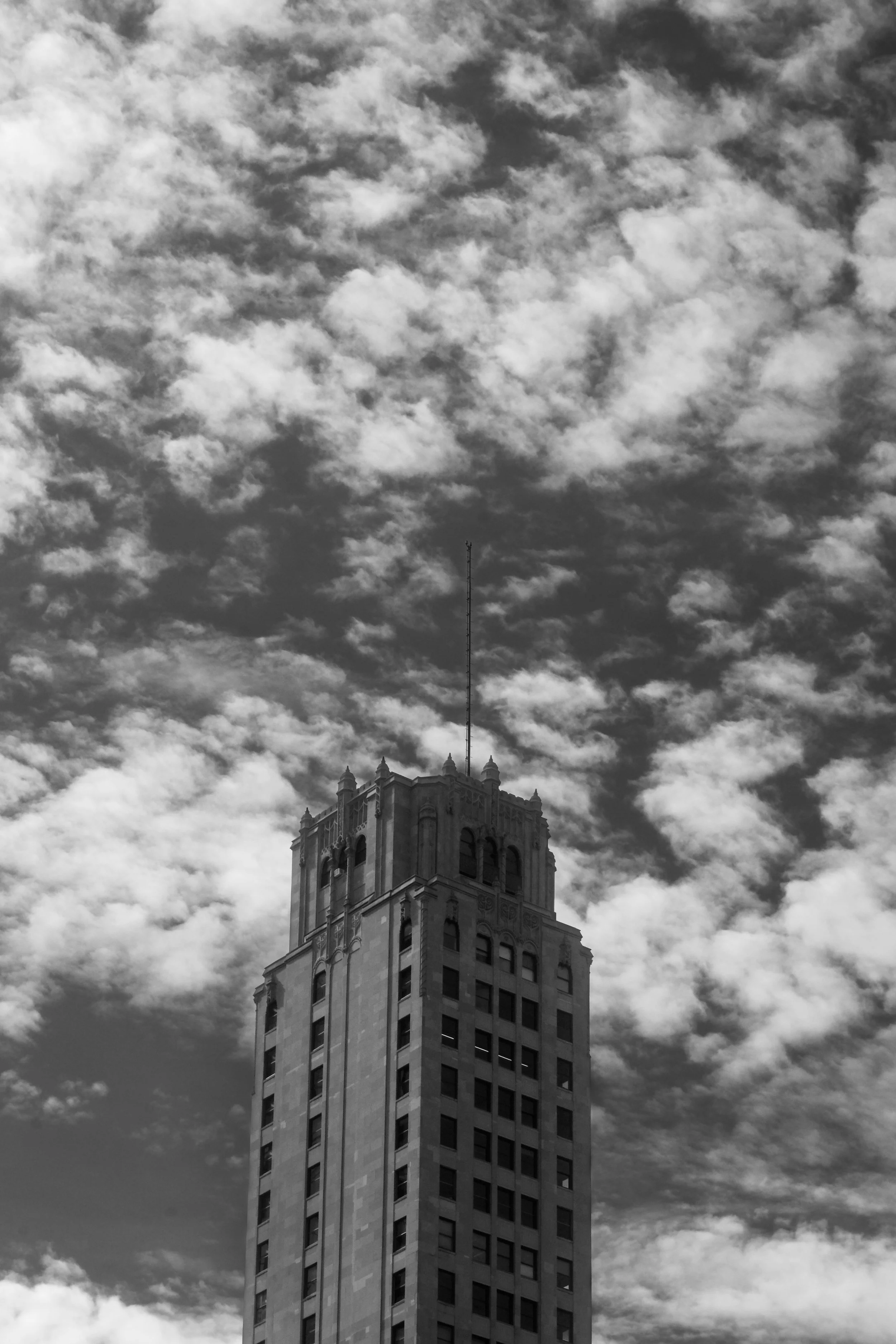 A tall skyscraper with a decorative top section, set against a partly cloudy sky.