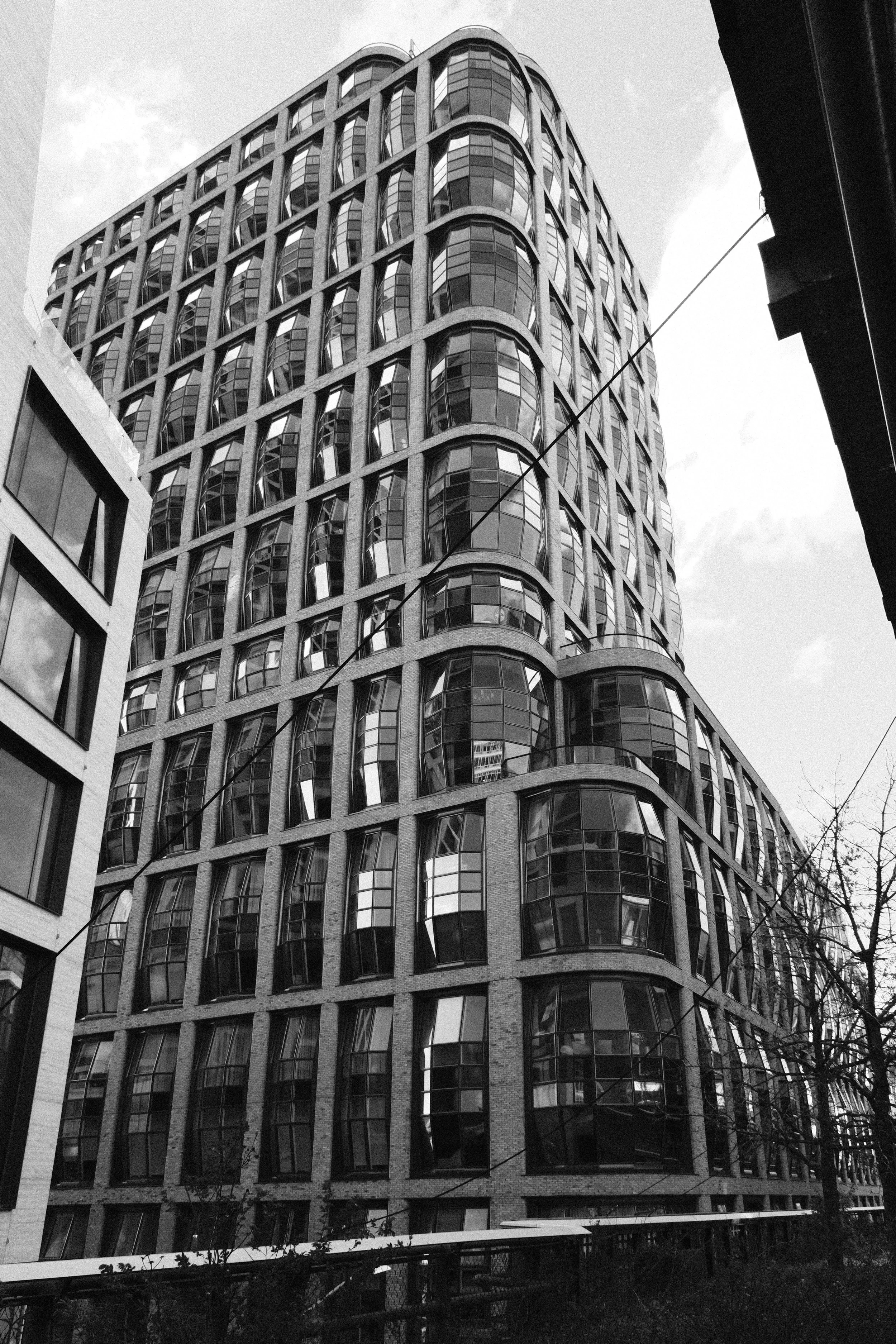 Black and white photo of a modern, multi-story building with rounded glass windows and a distinctive, wave-like architectural design.