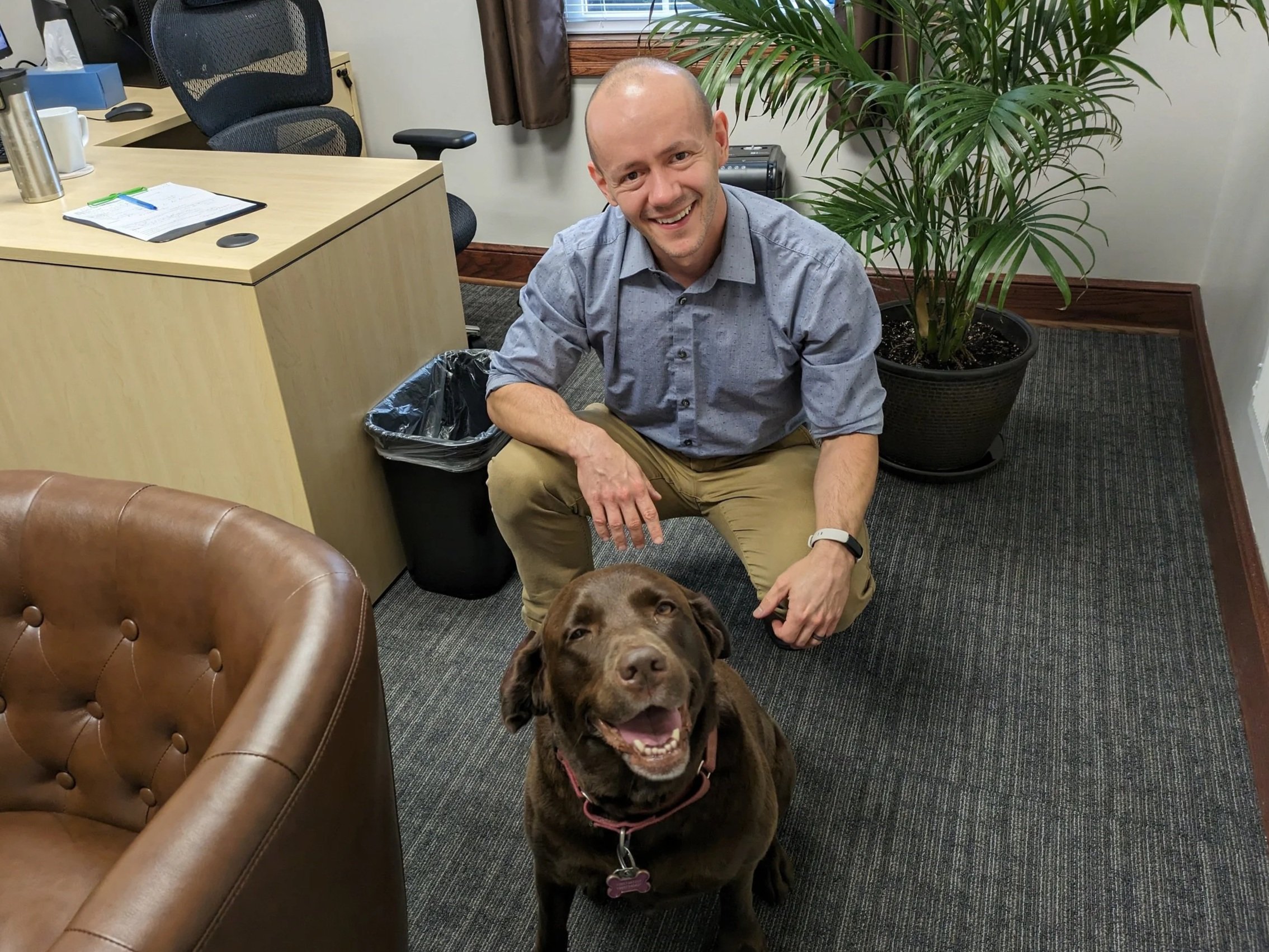 Dr. Adam Simning, an MD/PhD physician coach, in his office with his dog, symbolizing identity beyond the white coat.