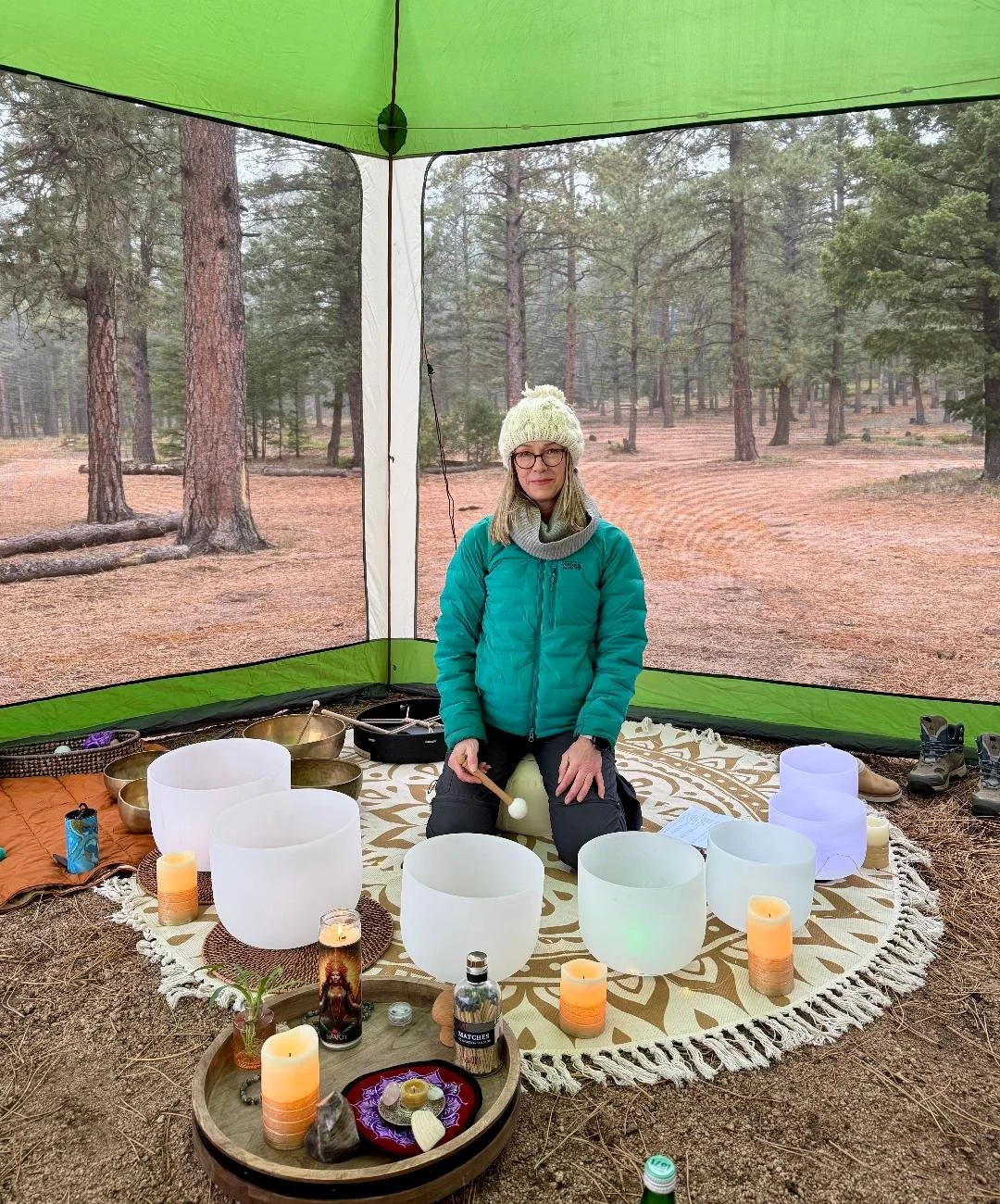 Betzy leading a sound bath in a tent surrounded by bowls and candles