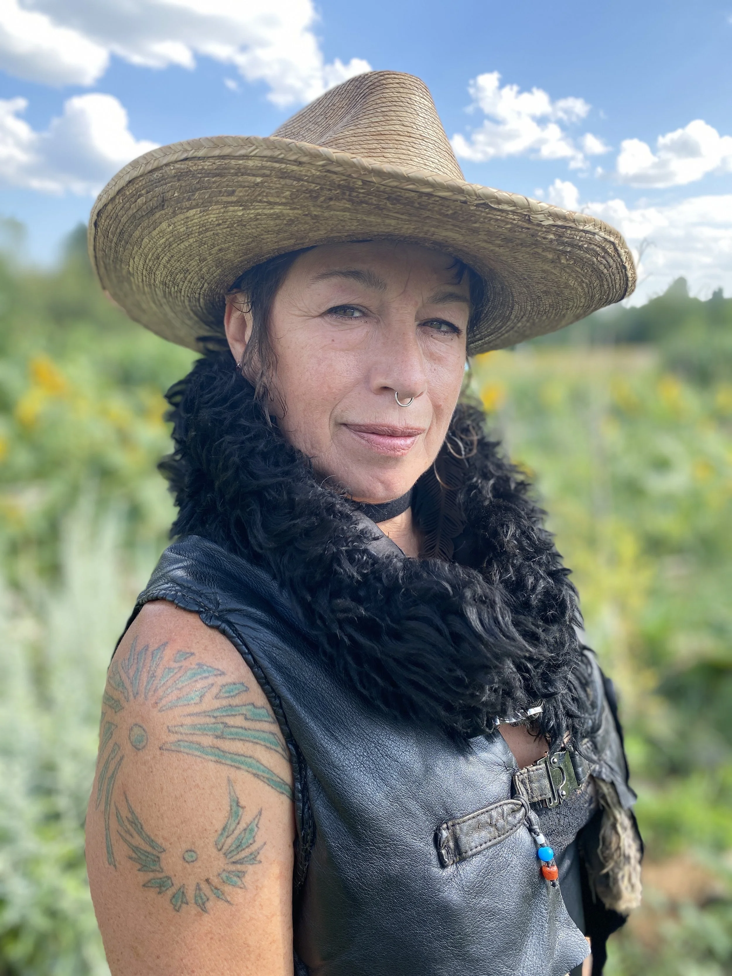 About Slava, gestalt psychotherapist in Ontario. Looking directly into the camera with a grounded confidence and ease. Slava's wearing a straw hat, leather vest and fur collar.