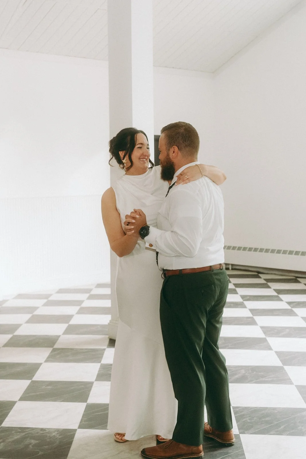 A couple dancing together indoors, smiling and looking into each other's eyes.