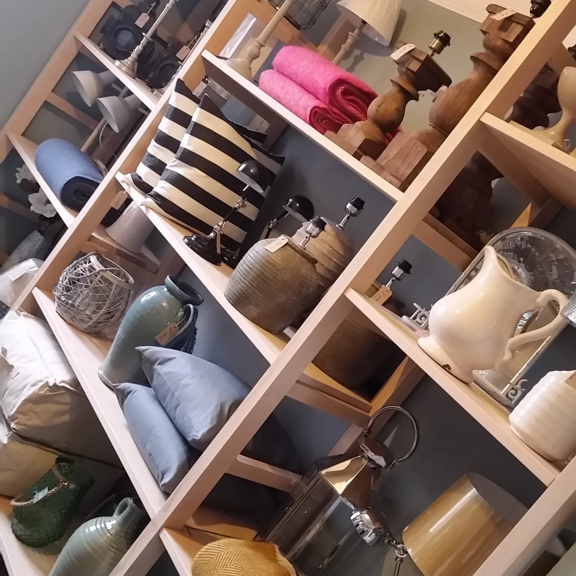 Shelves filled with home decor items including pillows, vases, bowls, lamps, and candles.
