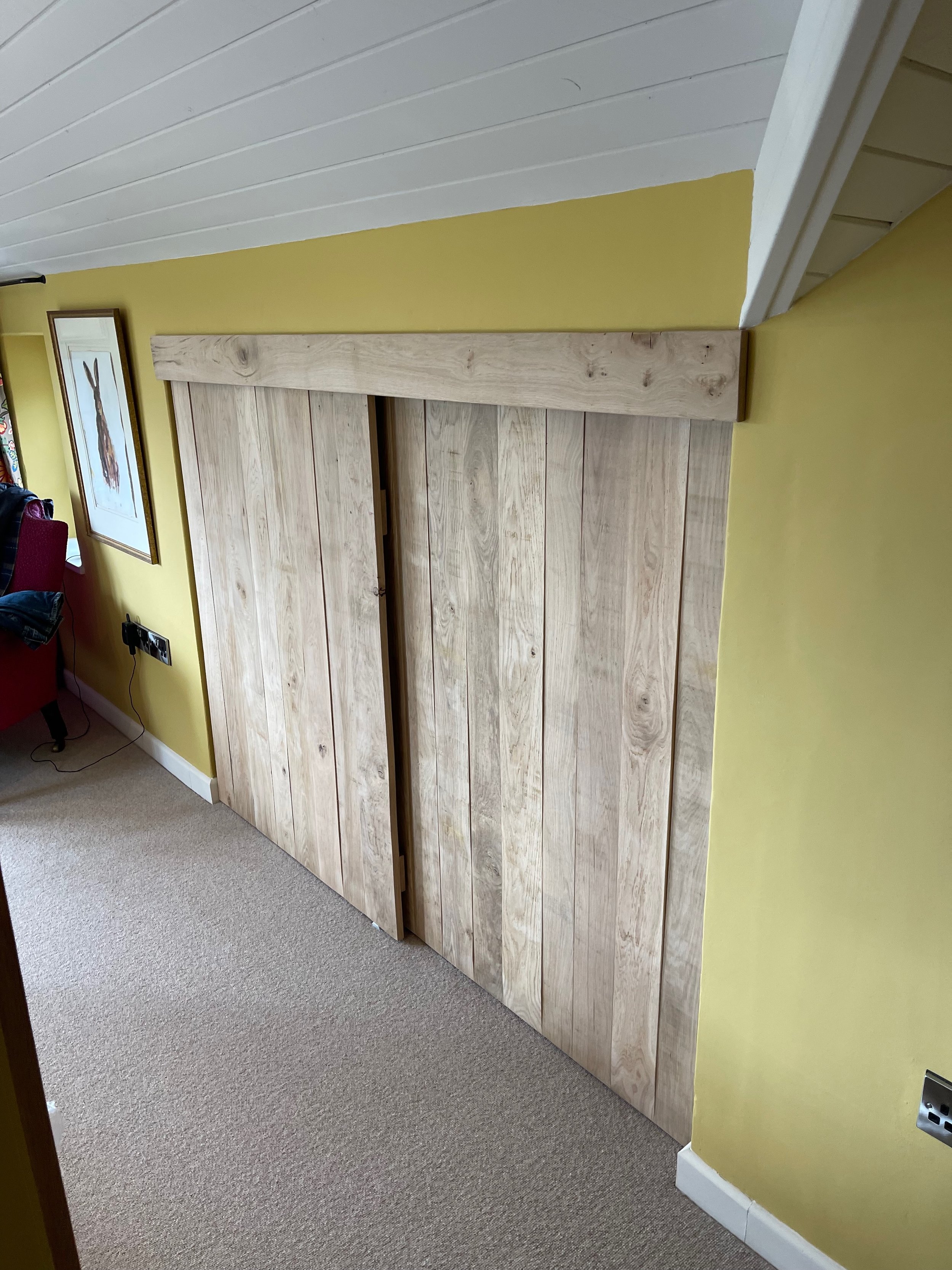 Wooden sliding barn door installed in a yellow wall room, with a portion of the ceiling visible.