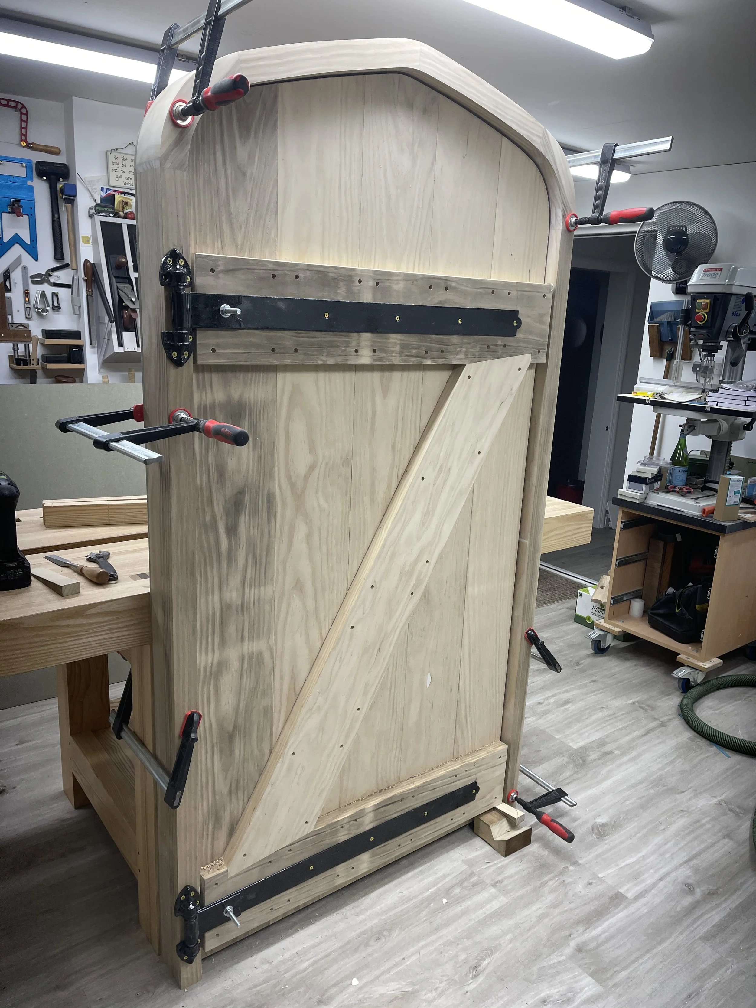 Woodworking project in progress, large wooden structure held together with clamps in a workshop.