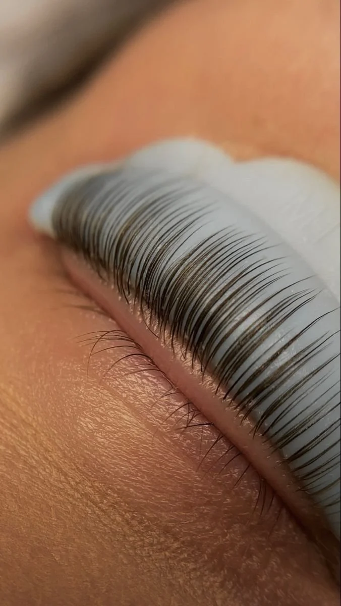 Close-up of a person's closed eye with long, curled mascara-coated eyelashes.