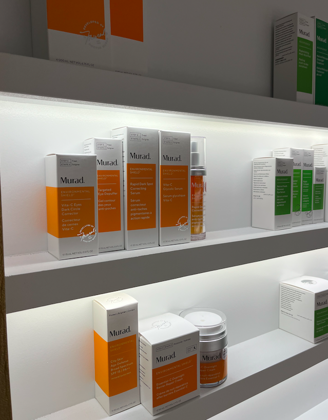 Shelf displaying Murad skincare products, including targeted eye treatment and correcting serums, in white and orange packaging.