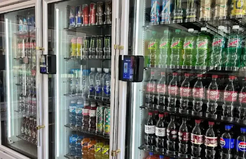 Refrigerated vending machines stocked with various bottles of soda, water, and soft drinks.