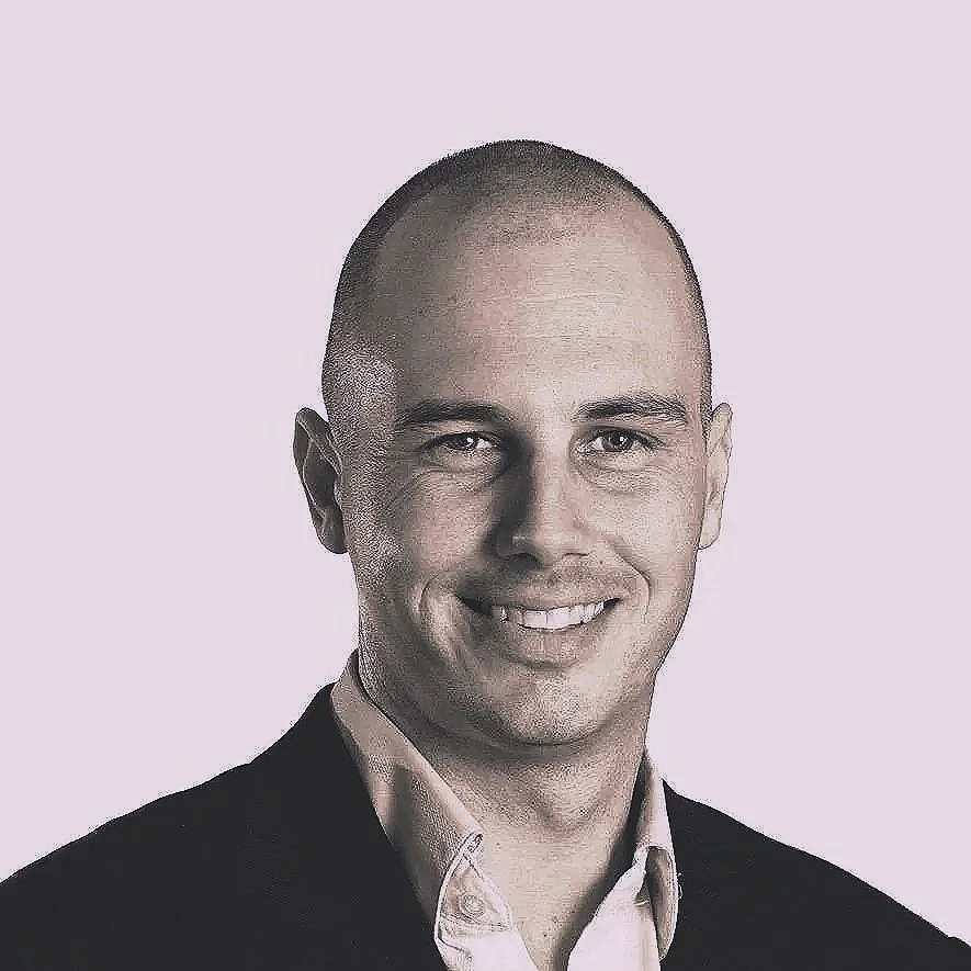 Black and white portrait of a smiling man in formal attire with a light background.
