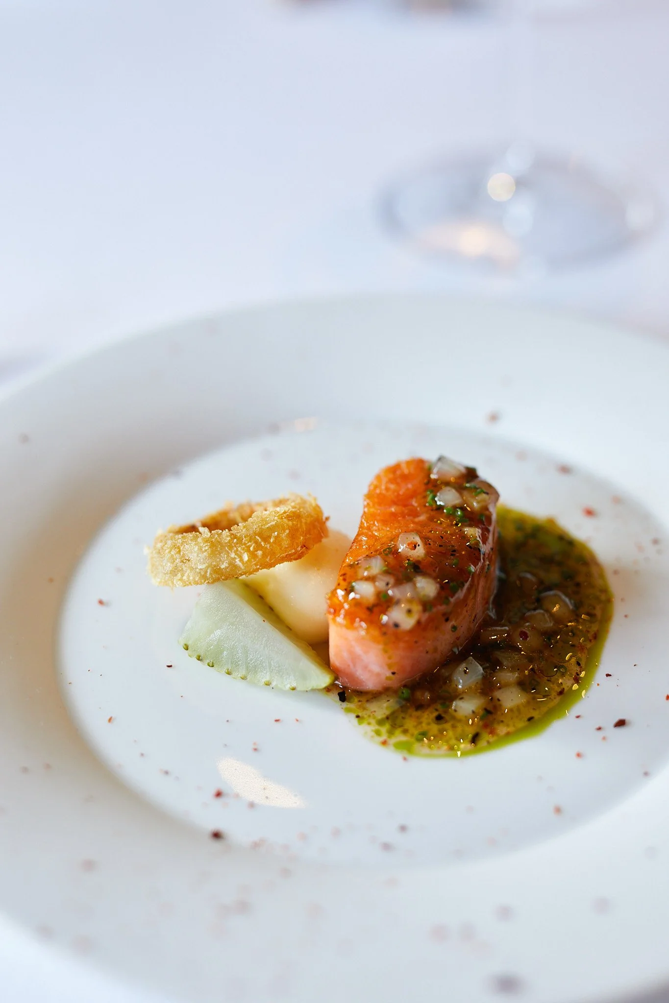 A plated gourmet dish featuring a piece of seared salmon with sauce at the French Laundry