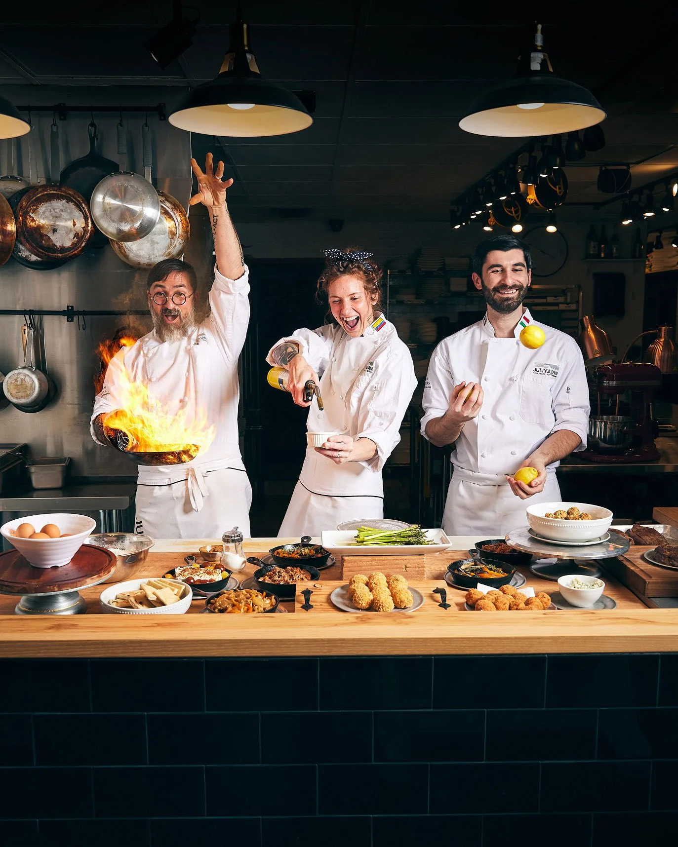 Three chefs showing off their skills with fire in Juli y Juan's Kitchen