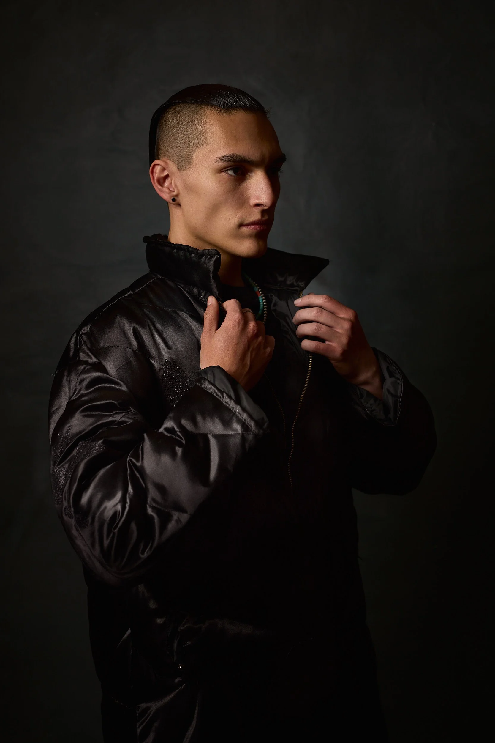 Fashion model wearing a black puffy coat in front of a dark background