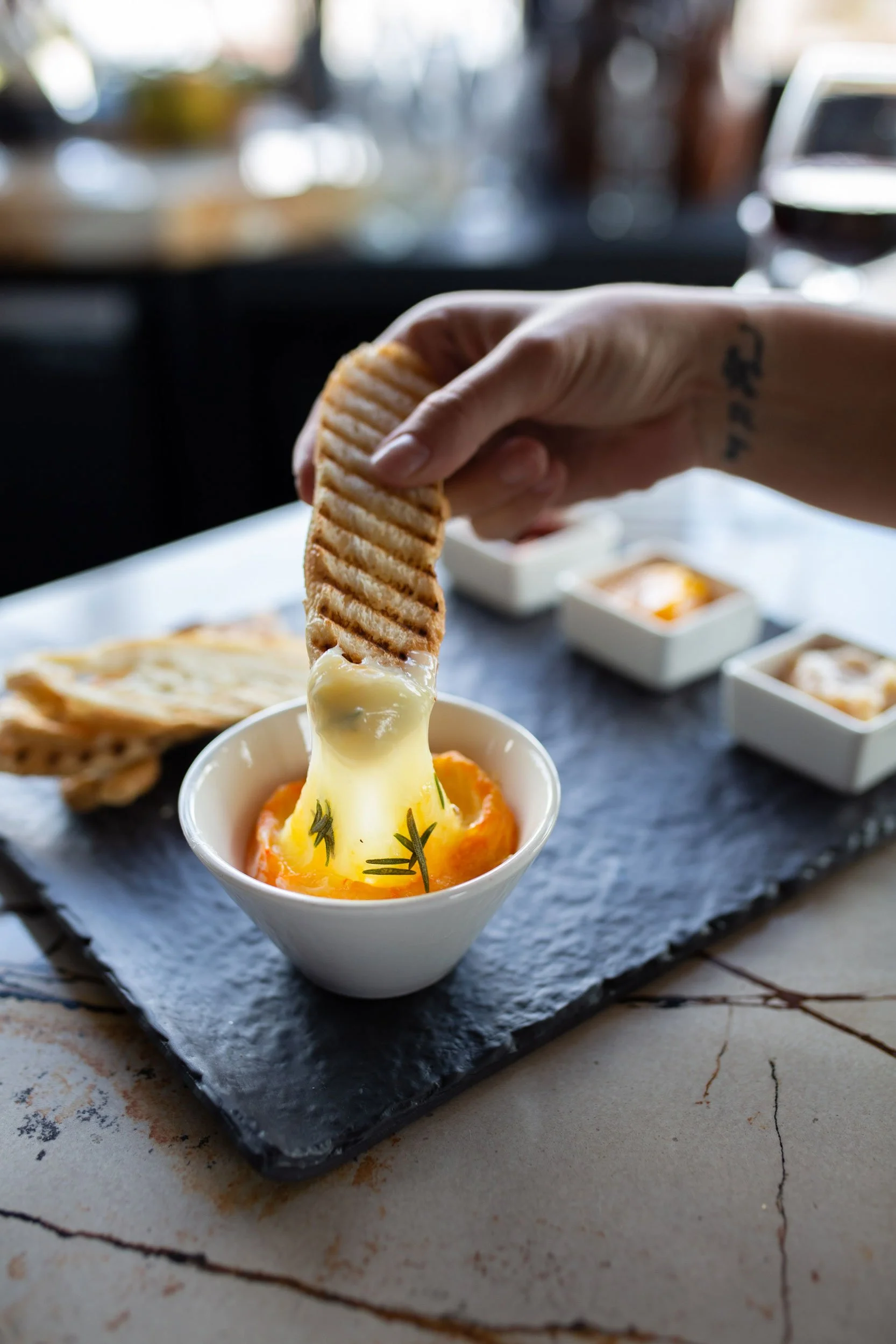 Crusty bread being dipped into a bowl of molten cheese at Ginger and Baker restaurant in Fort Collins Colorado