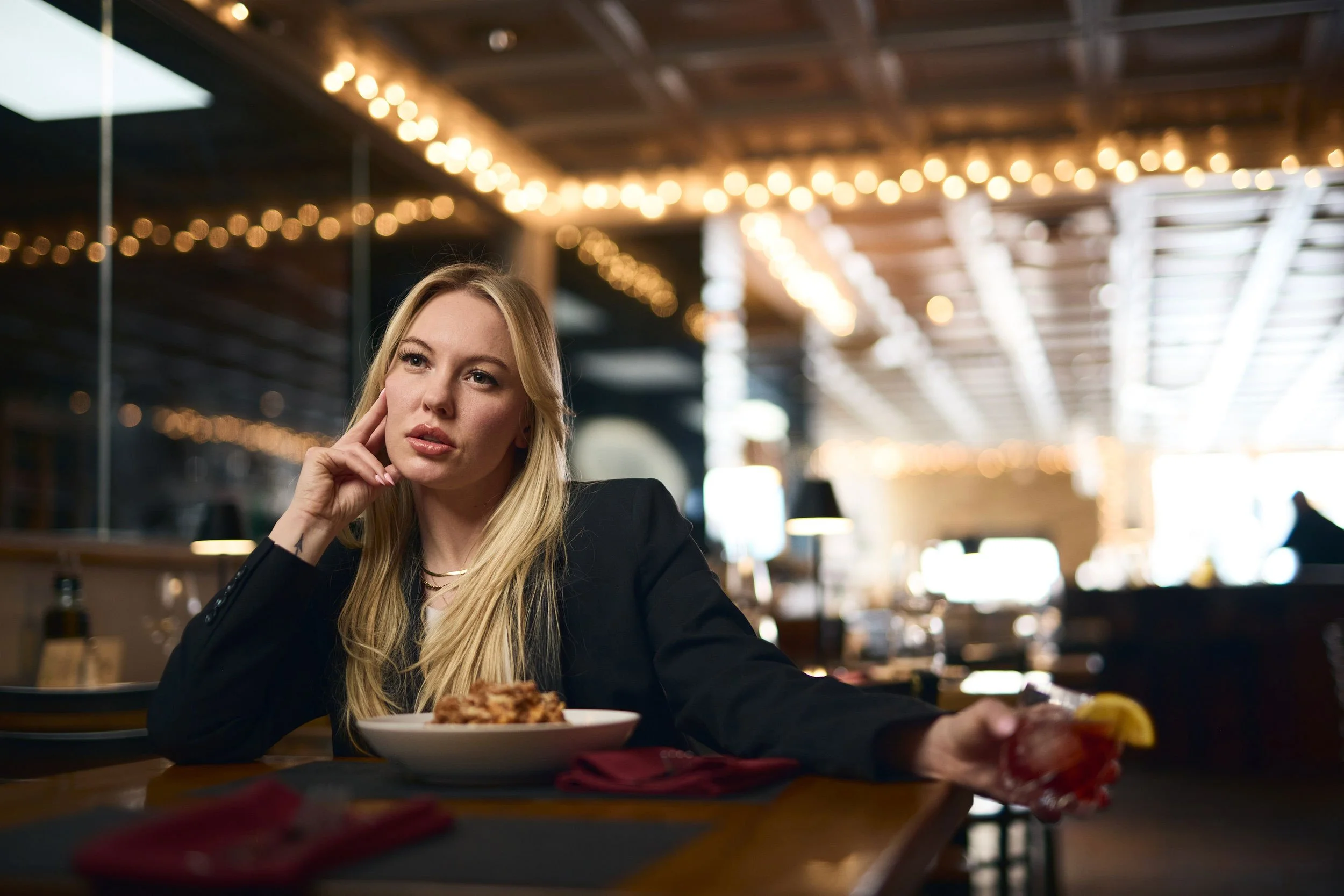 Female model sitting alone with a plate of bolognese and a negroni at Lo Stella in Denver