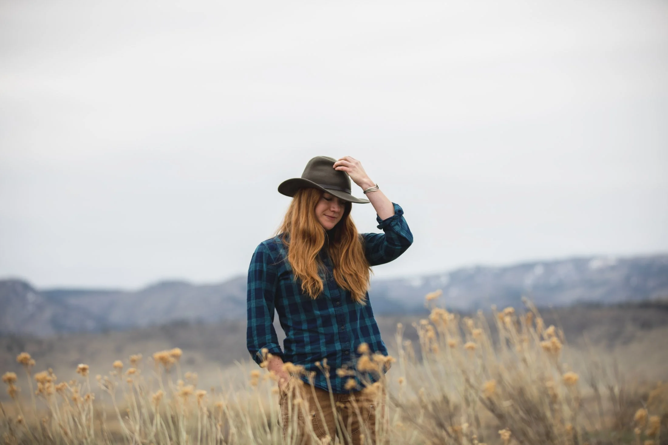Woman in a blue plaid Filson shirt in front of the Rocky Mountains
