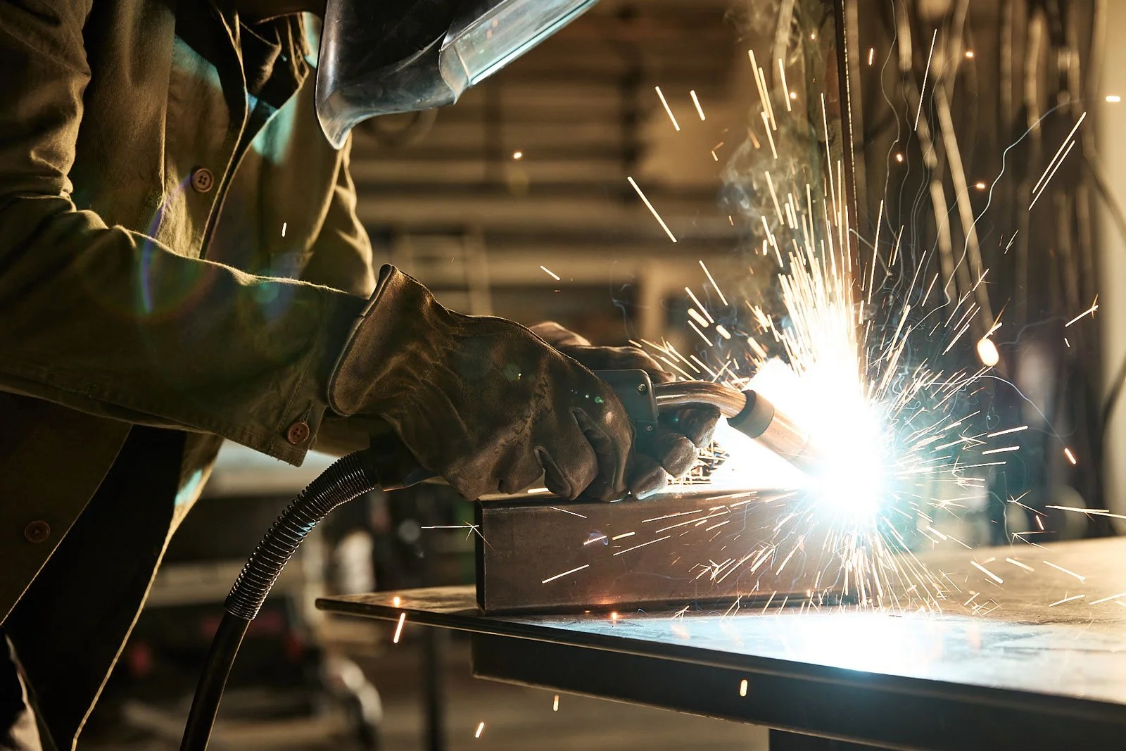 A person welding metal with sparks flying in a workshop.