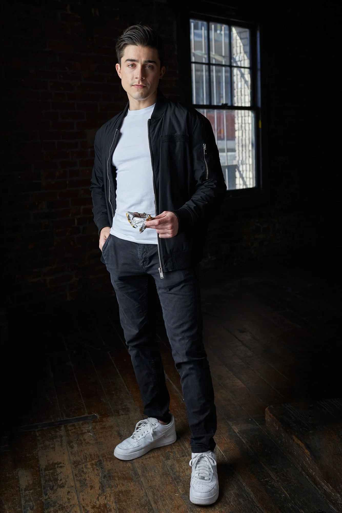 Model in a dark room holding a chocolate bar