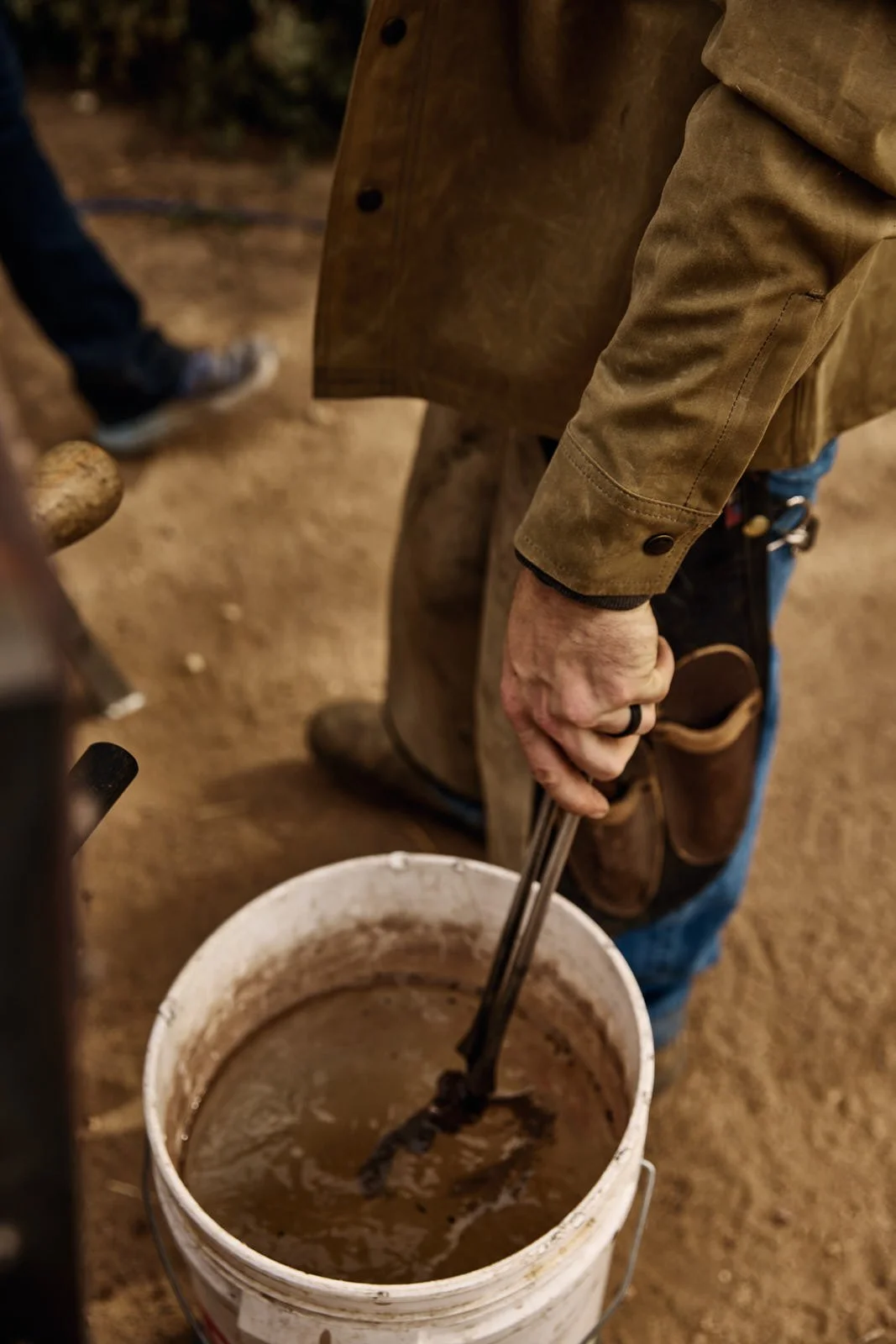 A person holding tongs in a white bucket filled with water.