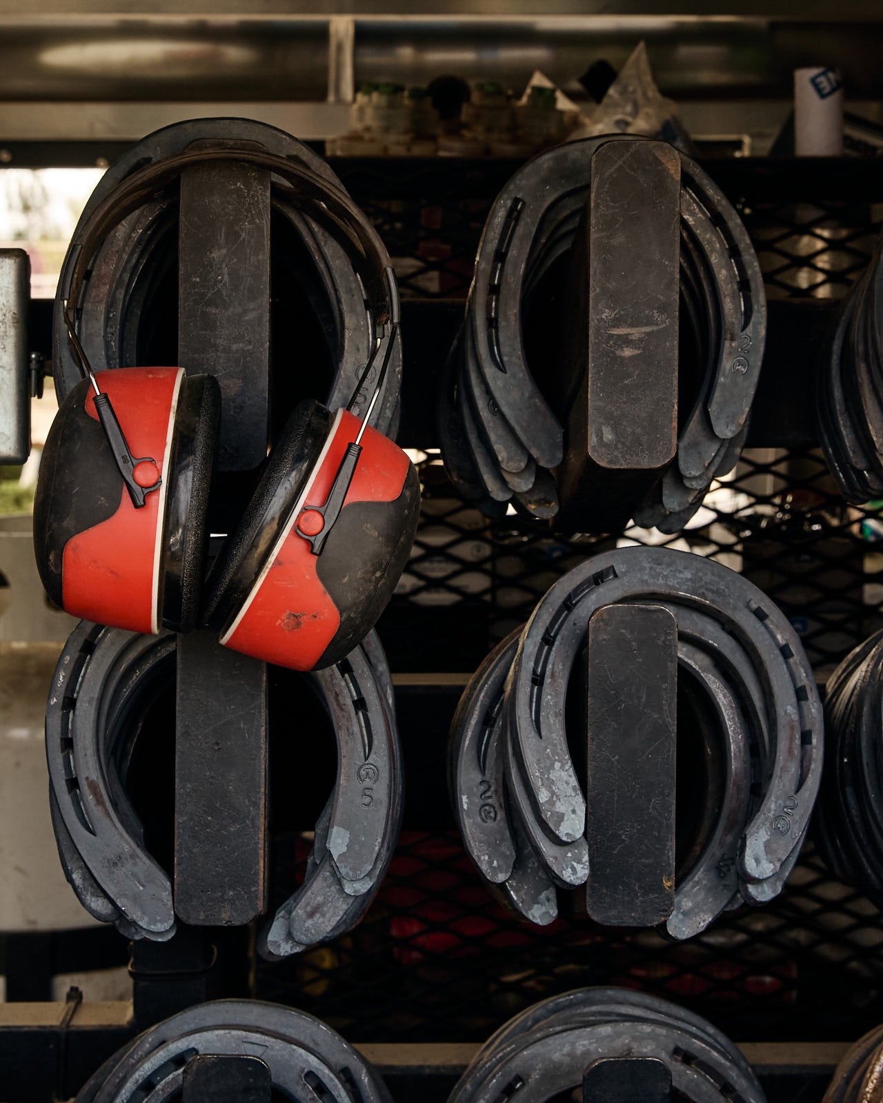 A shelf inside a truck holding multiple pairs of horseshoes