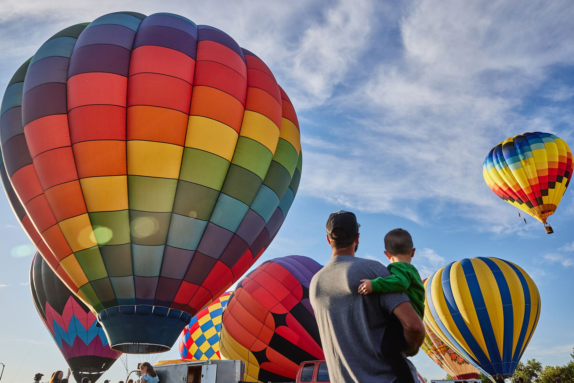 Man holding young son and watching hot air balloons take off