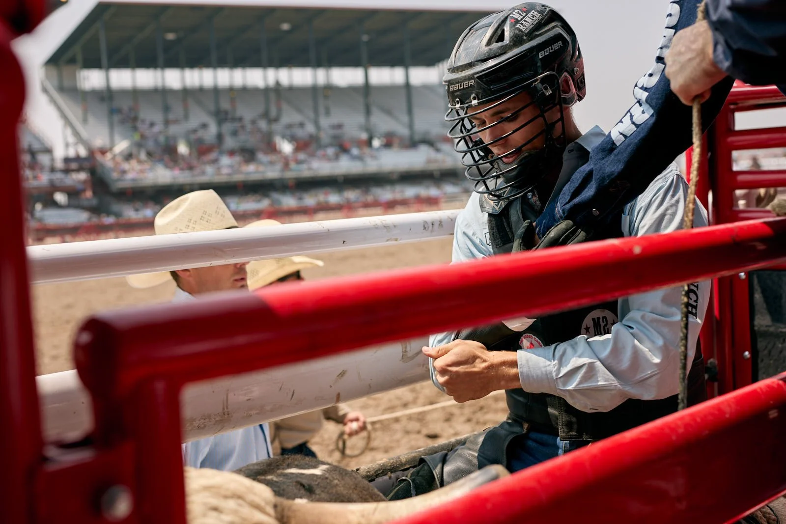 A young bull rider with helmet on bull in chute at a rodeo