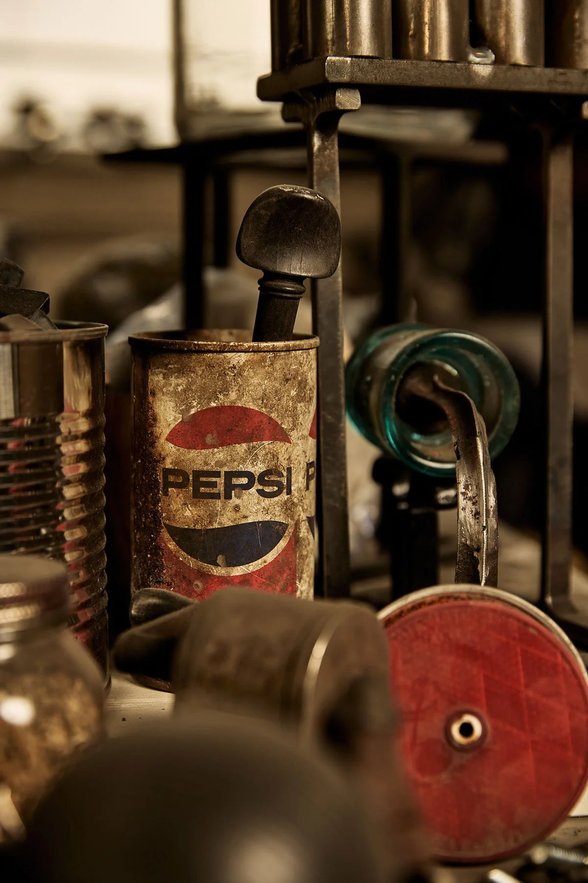 Vintage Pepsi soda can with a rusty and weathered appearance, surrounded by various old machinery and metal parts.