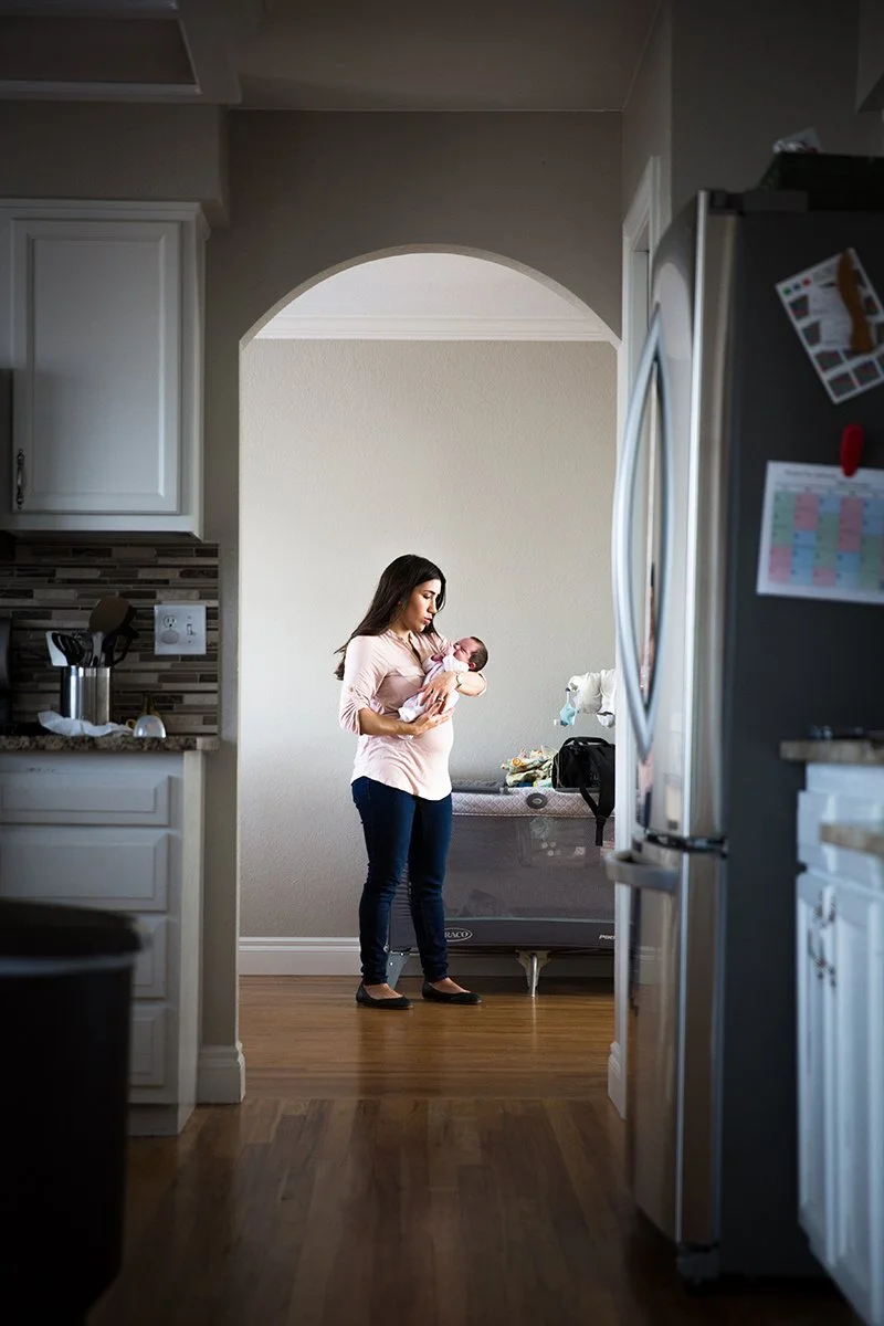 Woman holding her newborn in a doorway arch