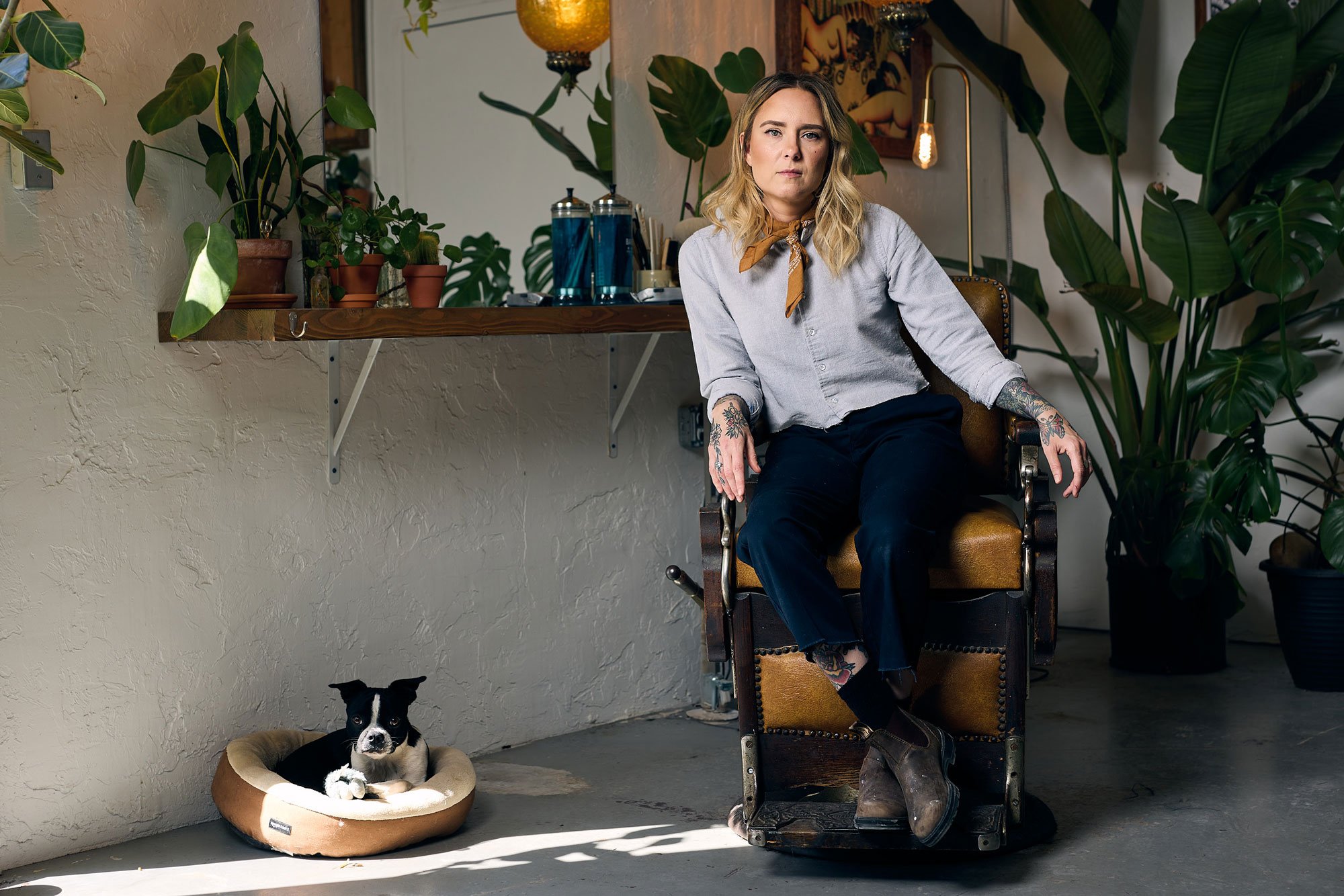 Female barber seated in a barber chair next to her Boston terrier