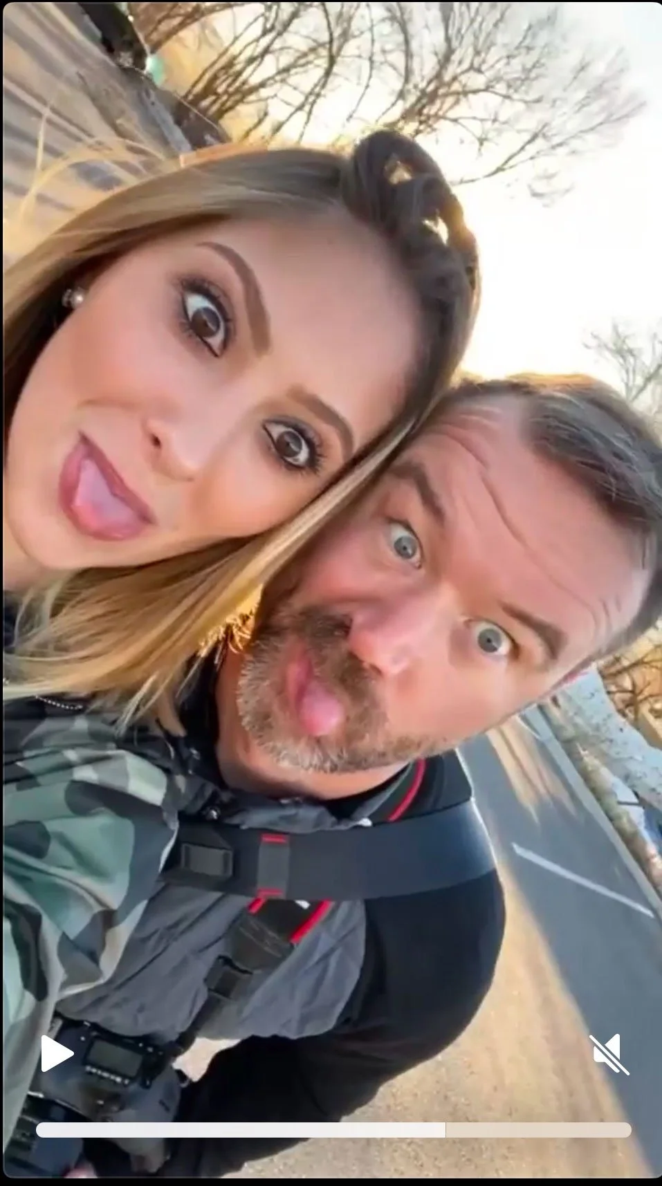 A young woman and photography John Robson are taking a selfie together outdoors, both sticking their tongues out and making funny faces