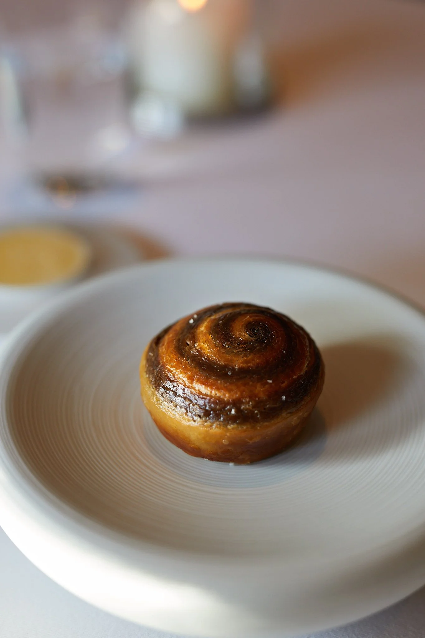 Close-up of a bread roll on a white plate, with blurred background at the French Laundry