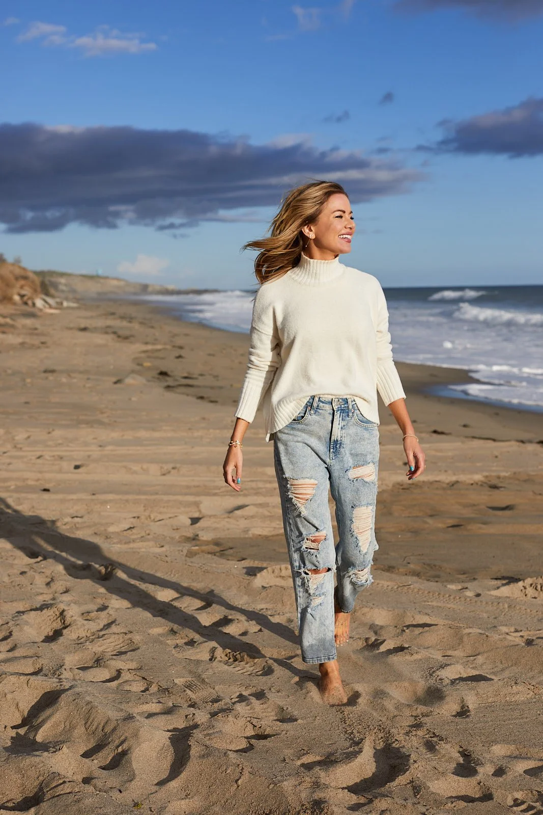 Model in ripped jeans walking on a California beach