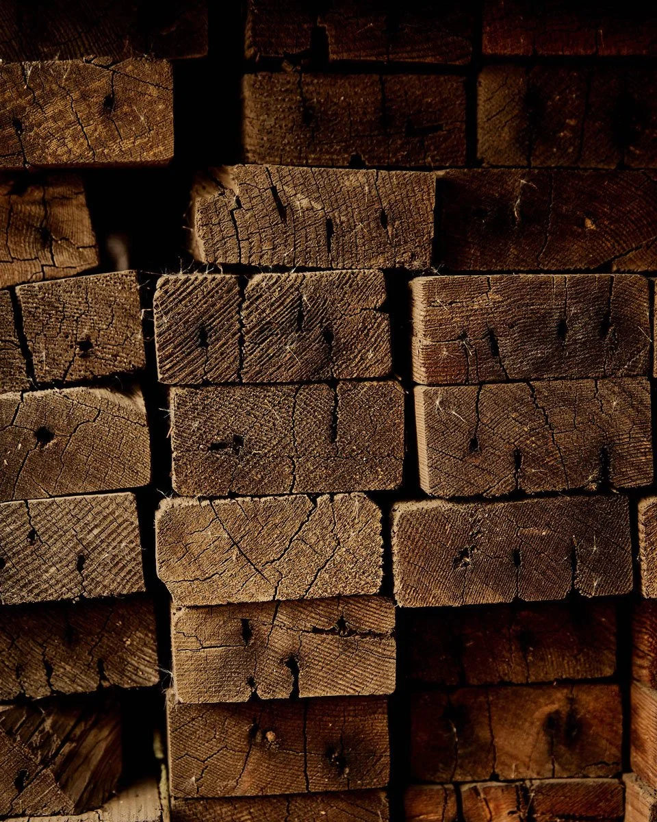 Stack of weathered wooden planks with visible grain and cracks.