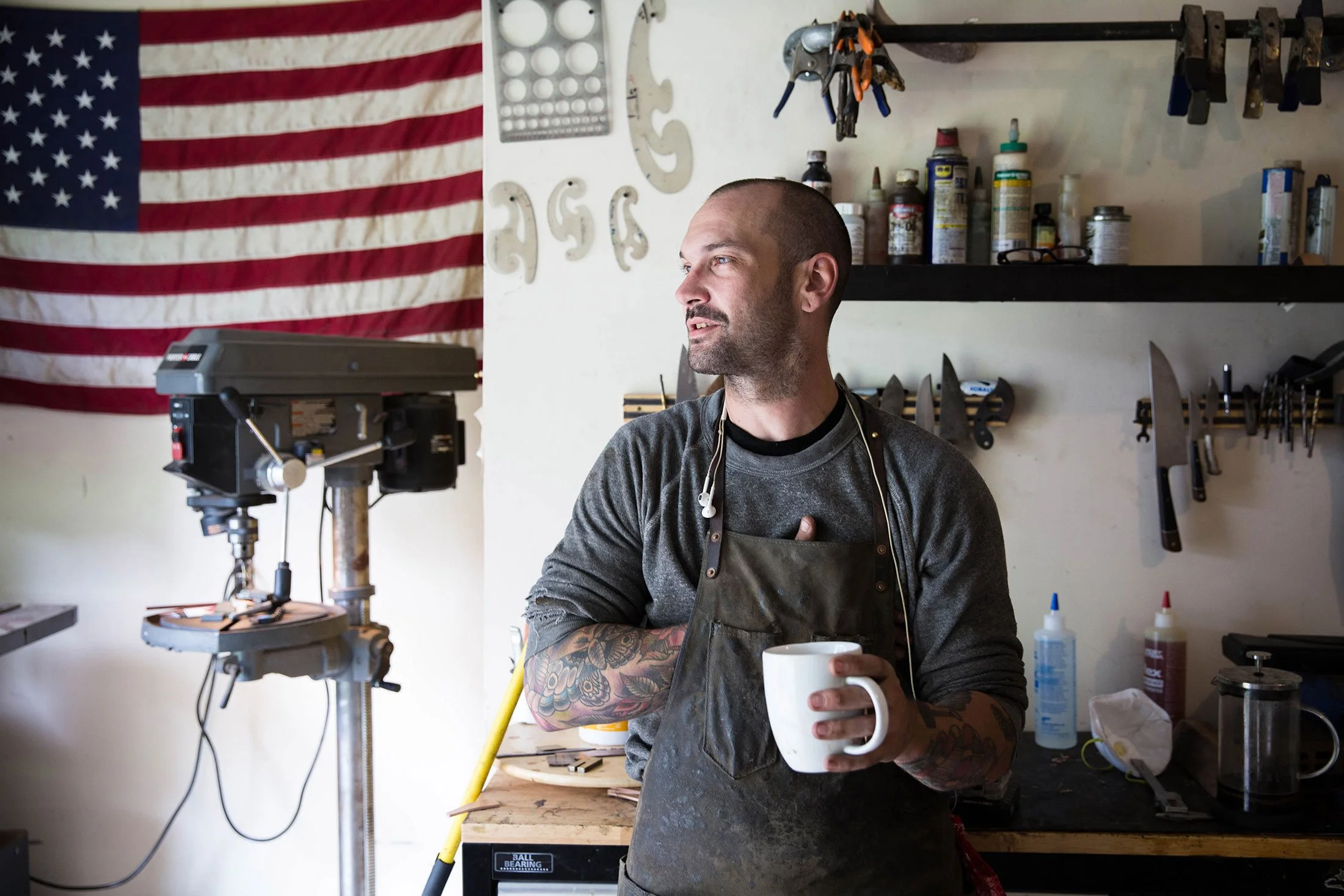 Knife maker holding a coffee cup and standing in his Austin Texas shop