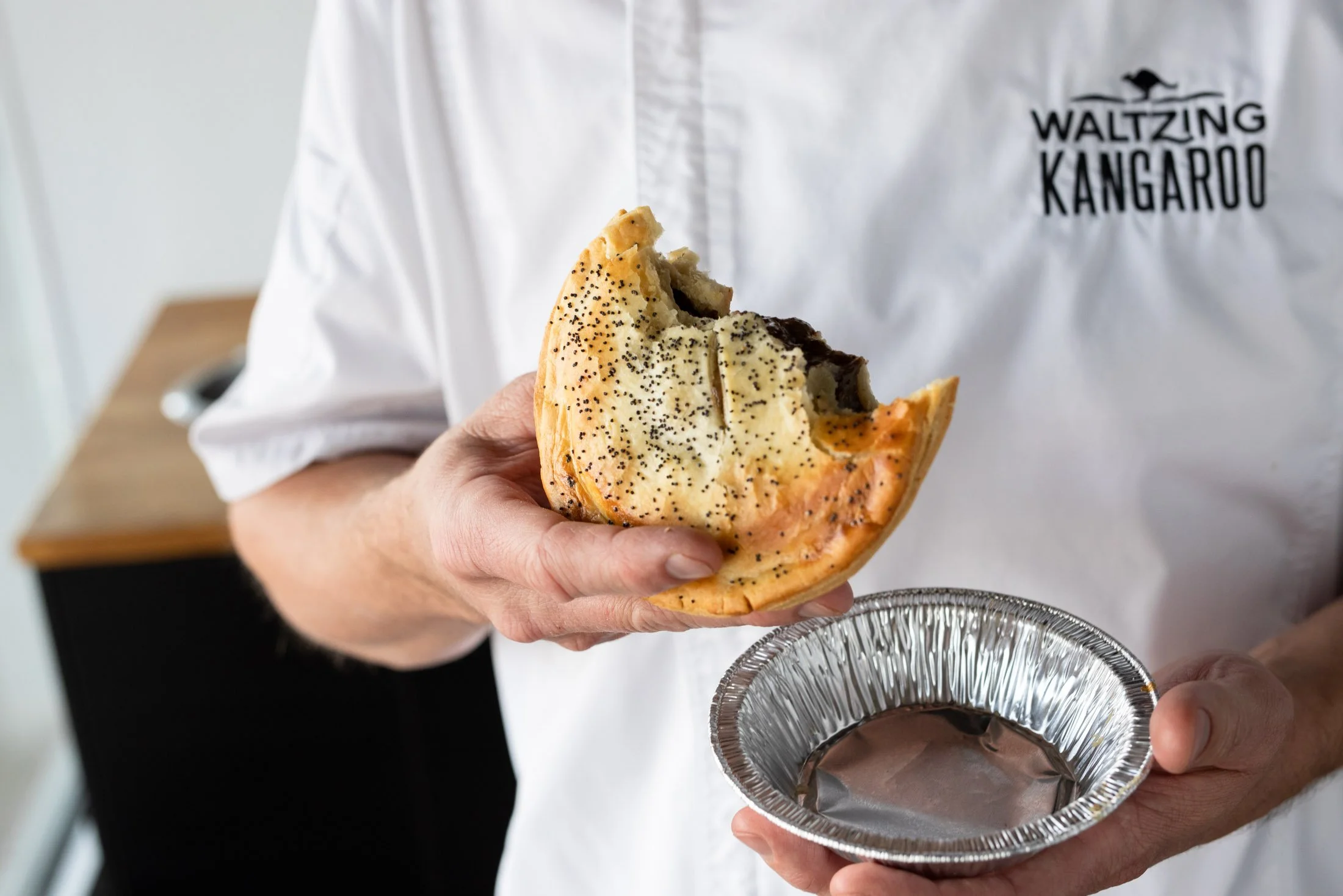 Owner of Waltzing Kangaroo restaurant holding a half eaten meat pie