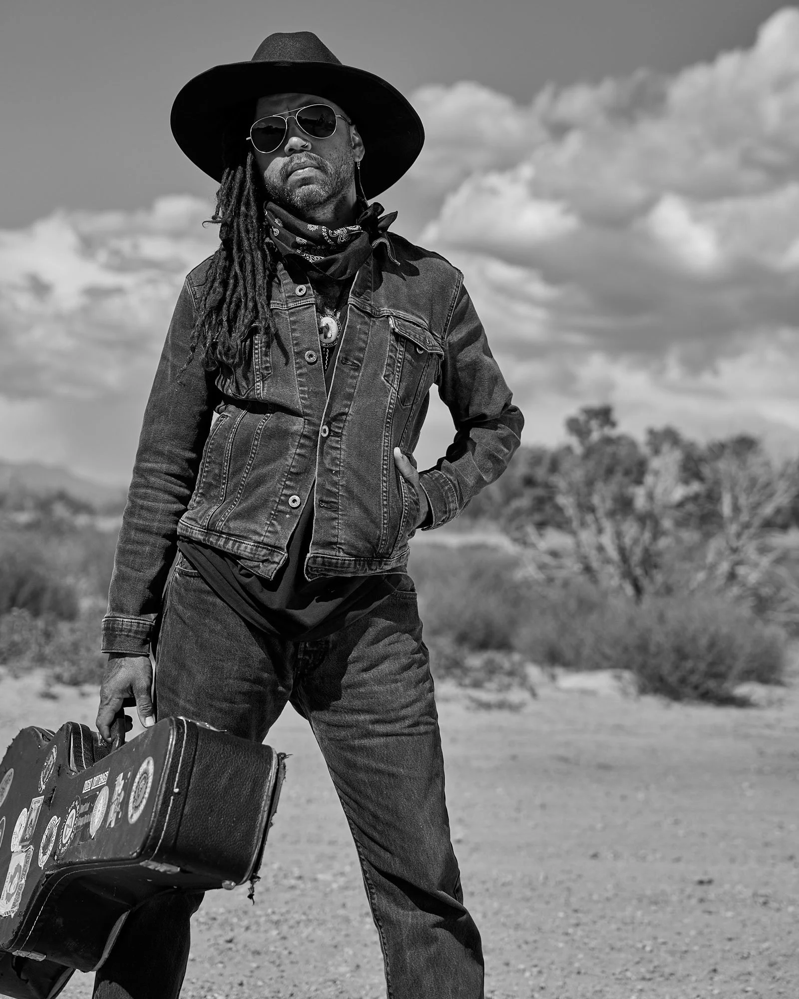 Black and white portrait of a musician standing outside in the American southwest