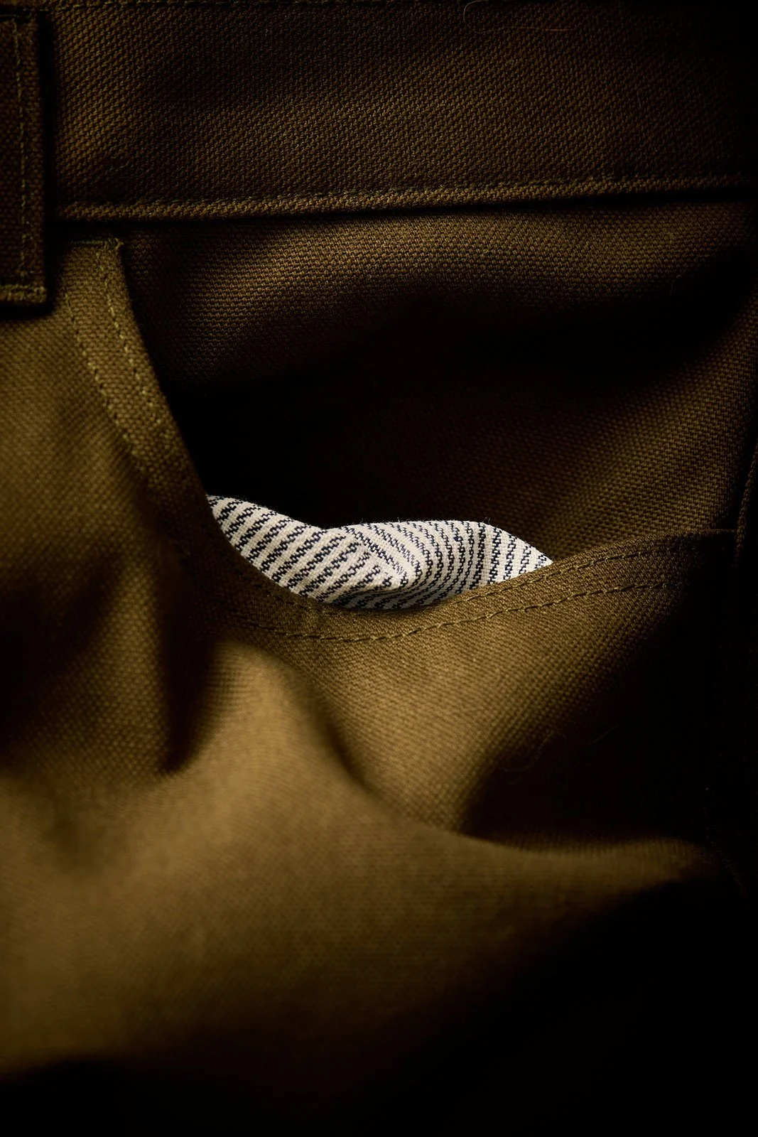 Olive drab pants with a striped cloth pocket.