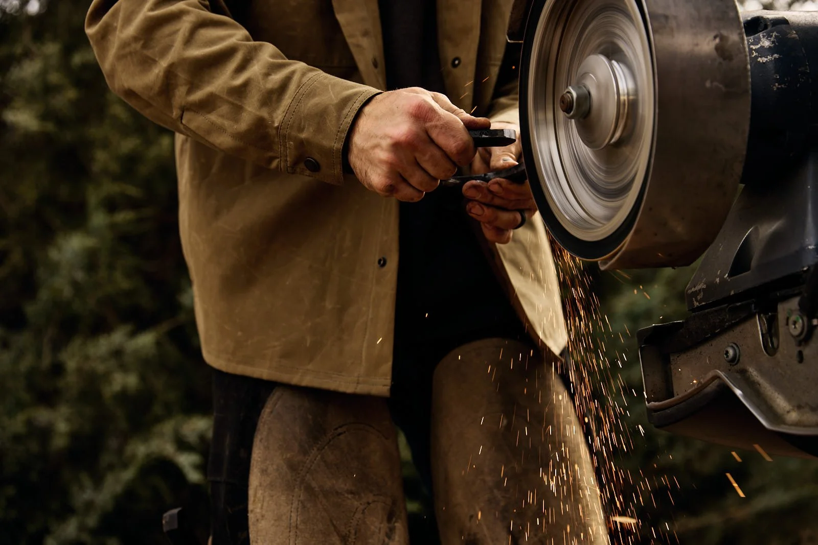 Person grinding a horseshoe on a machine, with sparks flying.