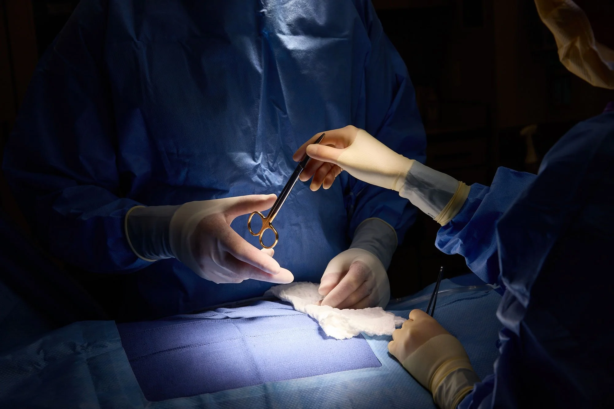 Plastic surgeon in OR being handed surgical scissors