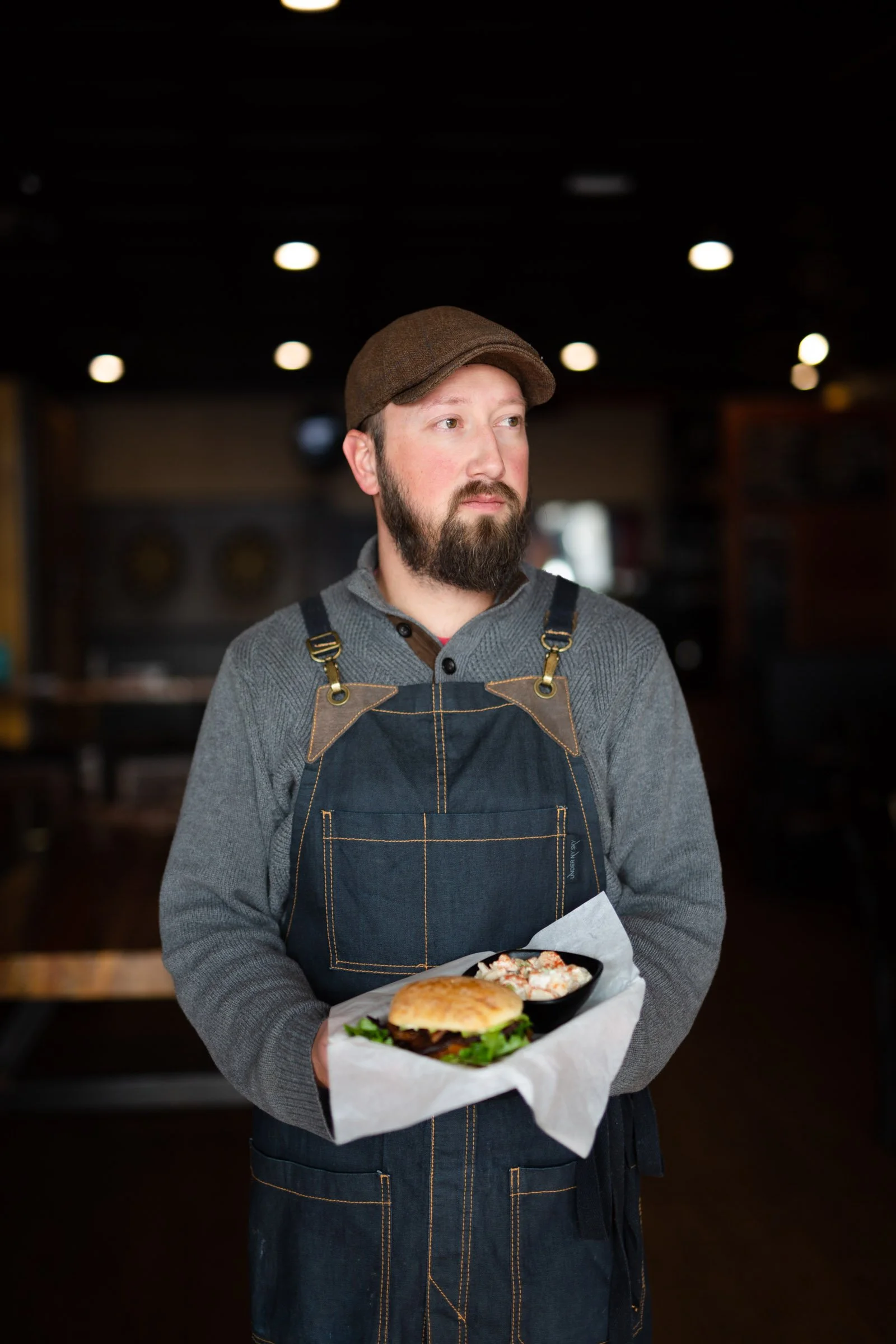 Owner of William Oliver restaurant holding a sandwich in the Fort Collins dining room