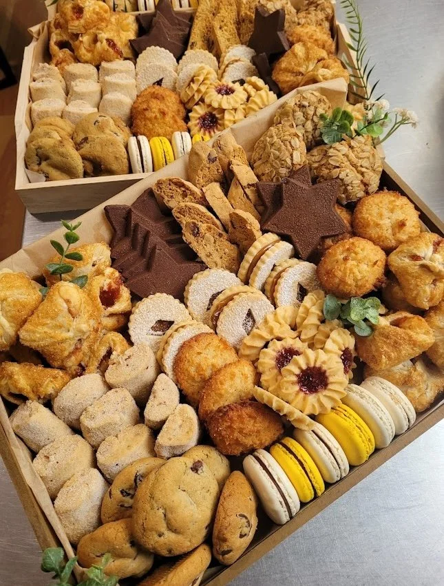 Assortment of handmade cookies and pastries arranged in wooden bakery boxes.