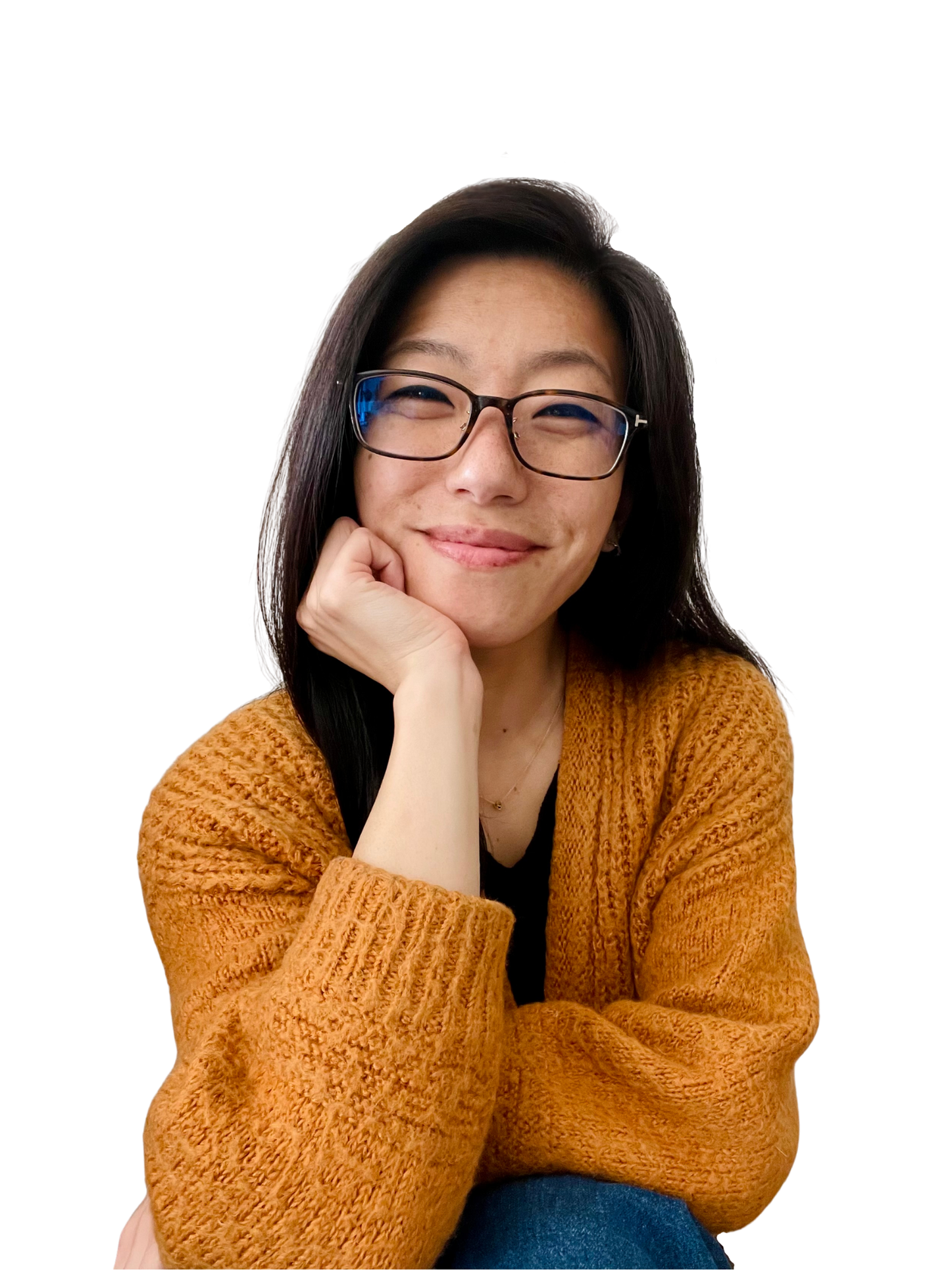 Clare Chi with glasses smiling, resting her chin on her hand, wearing a brown hoodie.