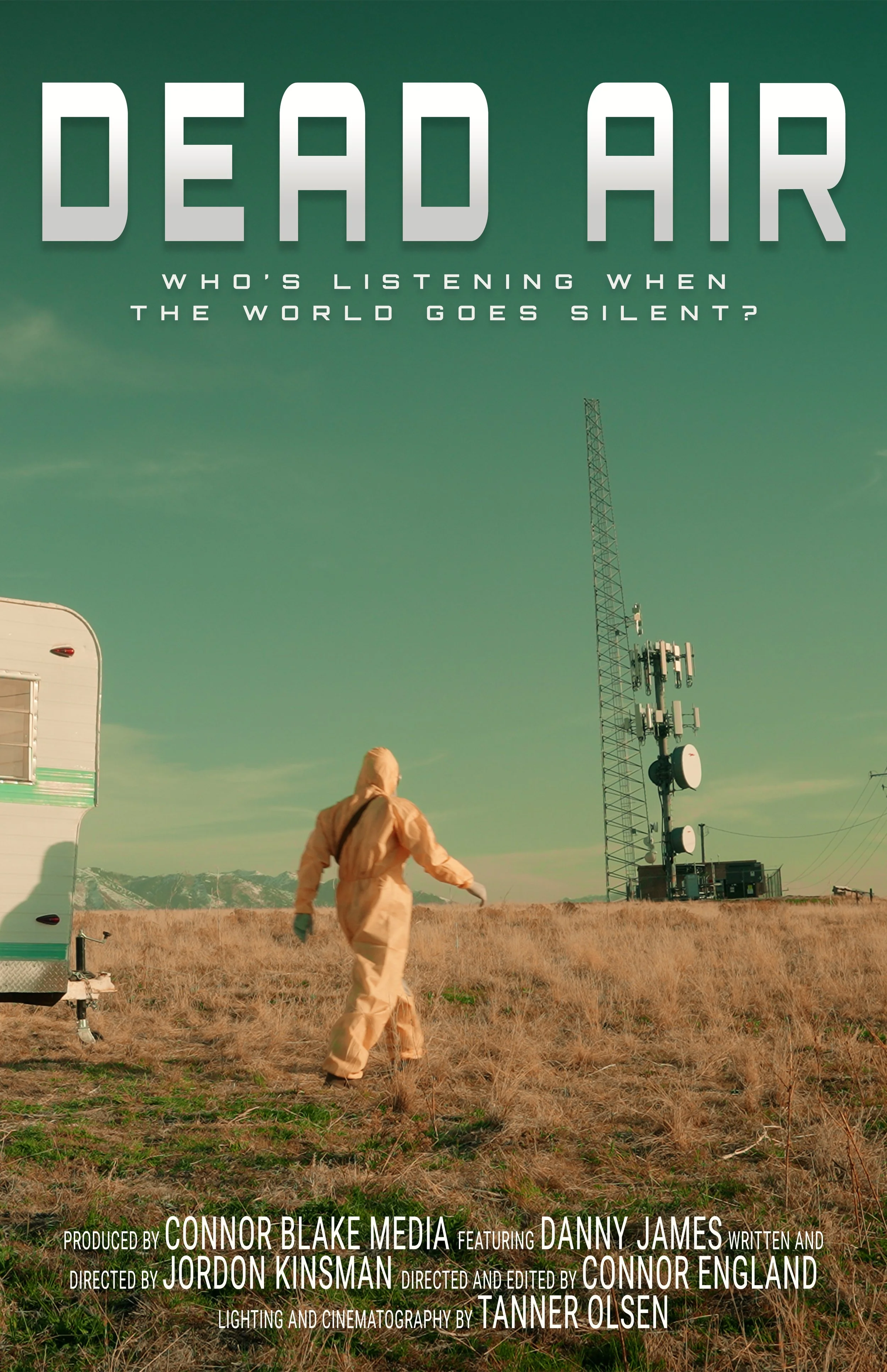 A person in a hazmat suit walking away in a field next to a trailer and communication towers with a mountainous background, under a greenish sky.