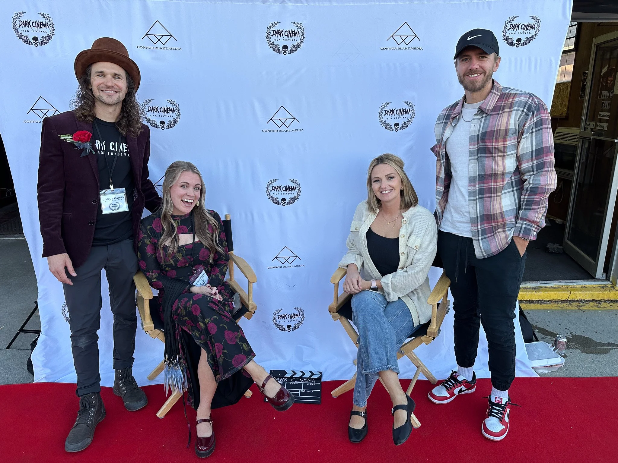Five people posing for a photo at a movie event, with some sitting and others standing, against a backdrop with logos for "Dark Cinema" and "Connor Blake Media."