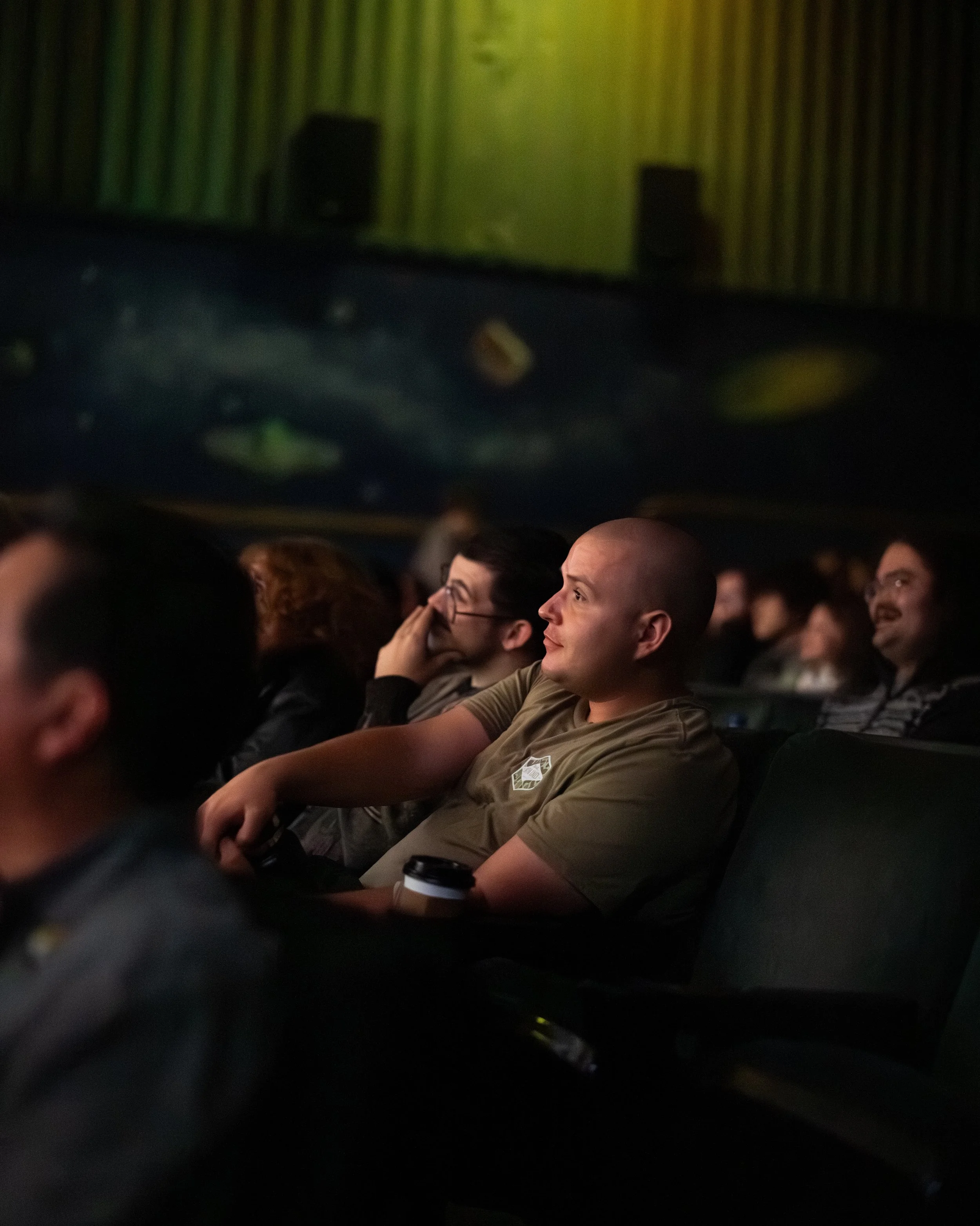People sitting in a movie theater watching a film with a space-themed scene on the screen.