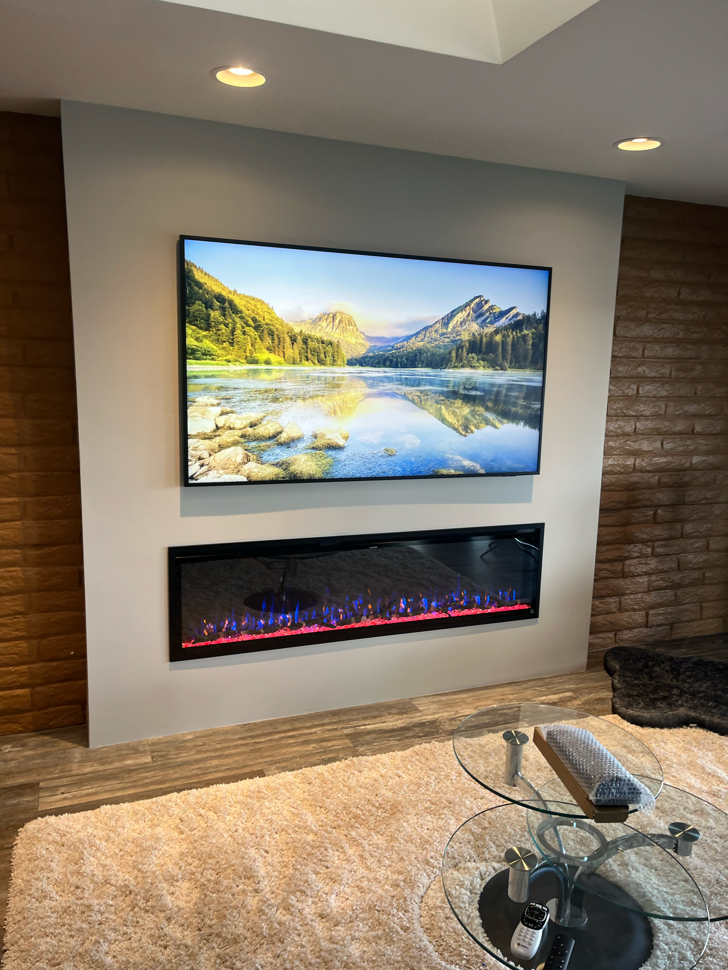 Modern linear electric fireplace installed beneath a wall mounted flat screen tv as a part of custom media wall in contemporary living room. Professionally designed and installed by Home AVTV & Design with concealed wiring and a clean look
