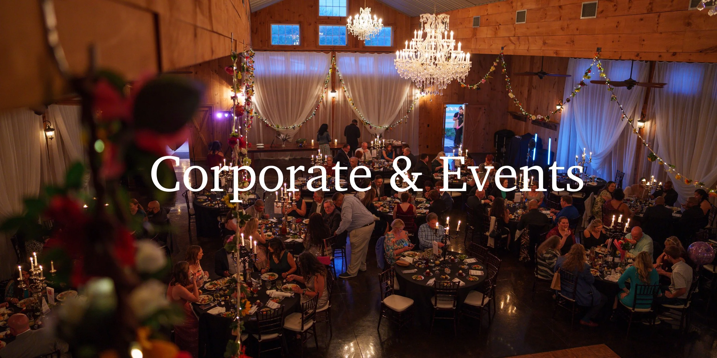 Elegant indoor event with round tables, chandeliers, candles, and floor-to-ceiling curtains, hosting a large crowd of people enjoying dinner.