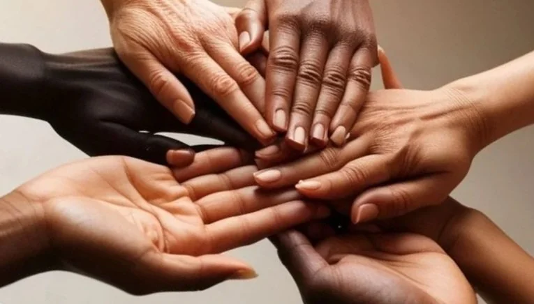 Multiple hands of diverse skin tones stacked together in a gesture of unity