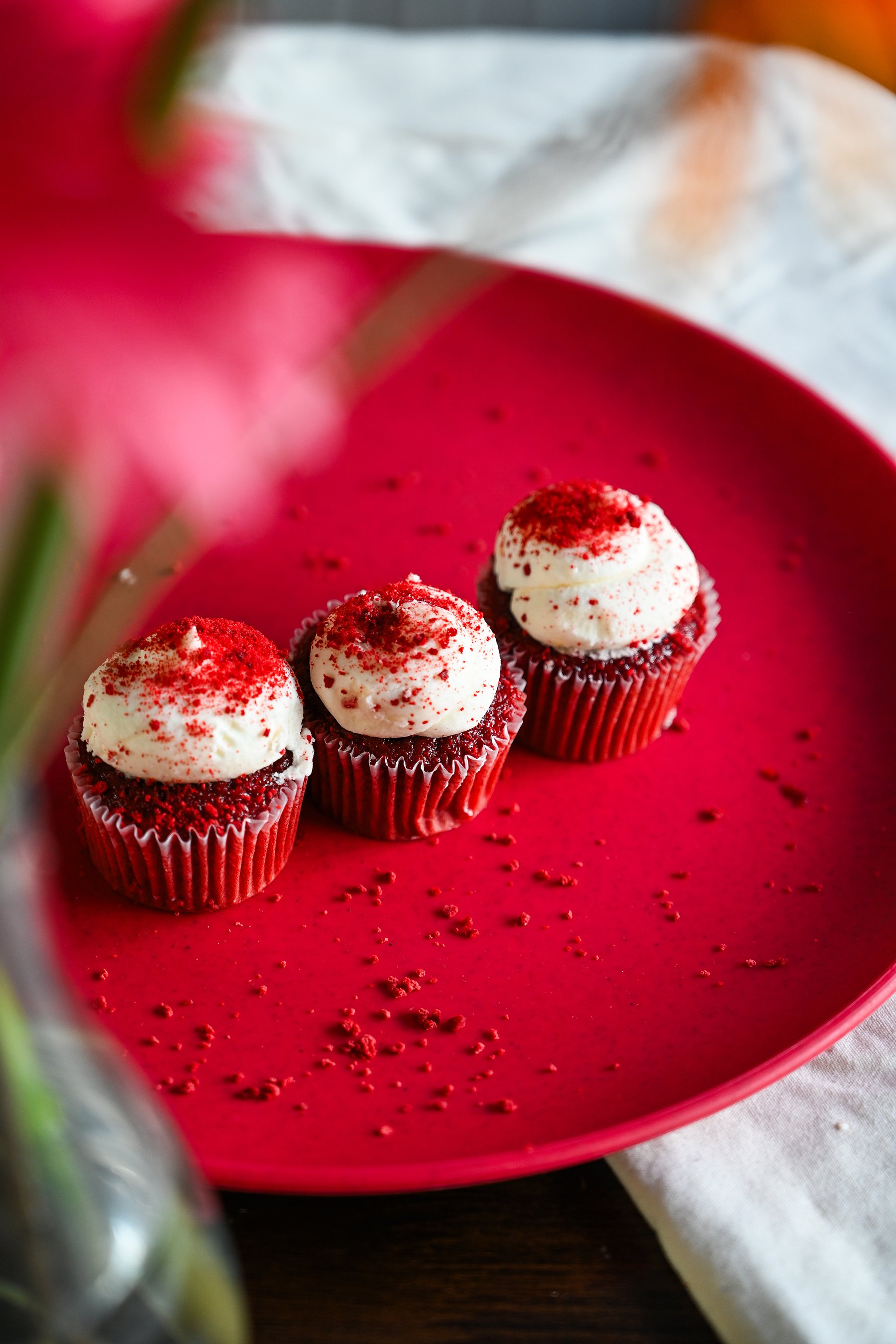 3 Red Velvet Cupcakes in a line behind flowers_small.jpg
