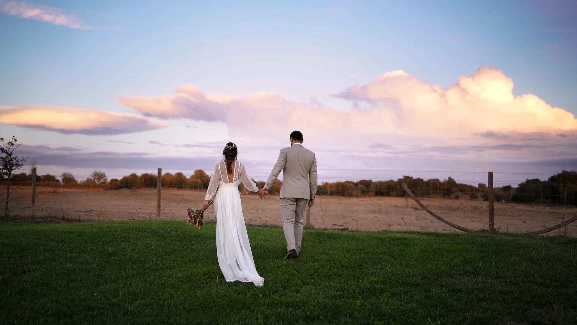 Casal de noivos caminhando de mãos dadas ao sunset num campo aberto em Montemor-o-novo no Alentejo