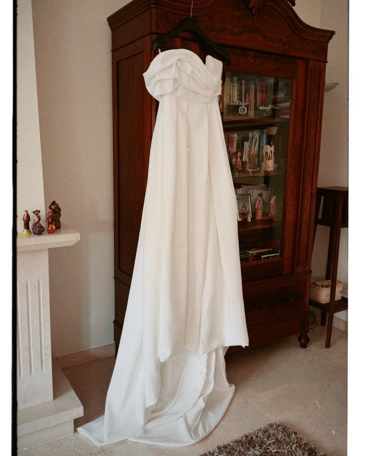 Vestido de casamento branco pendurado em cabide na mobília de madeira na sala